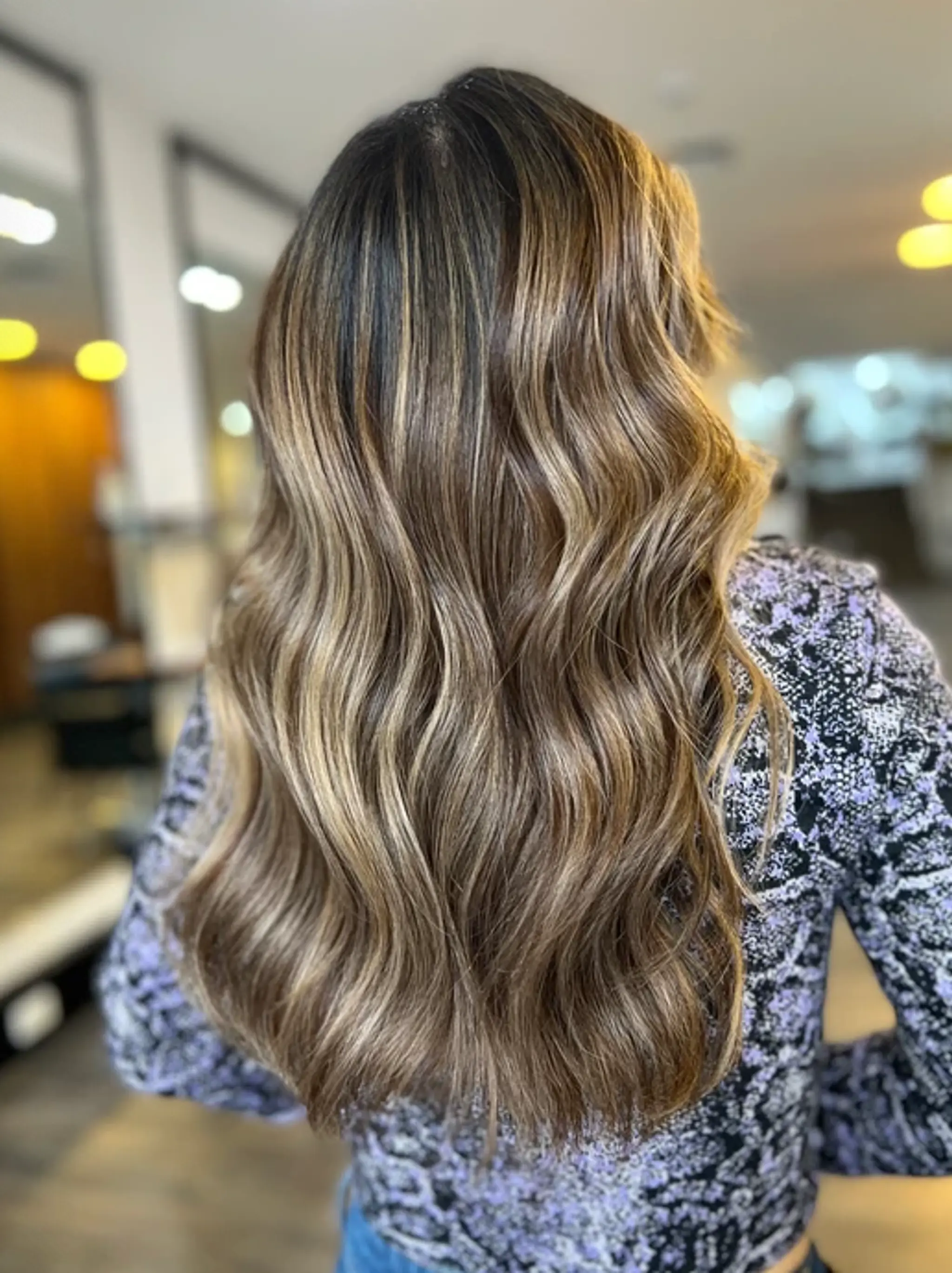 Long, multi-tonal wavy hair with soft, voluminous waves and a sun-kissed balayage effect.