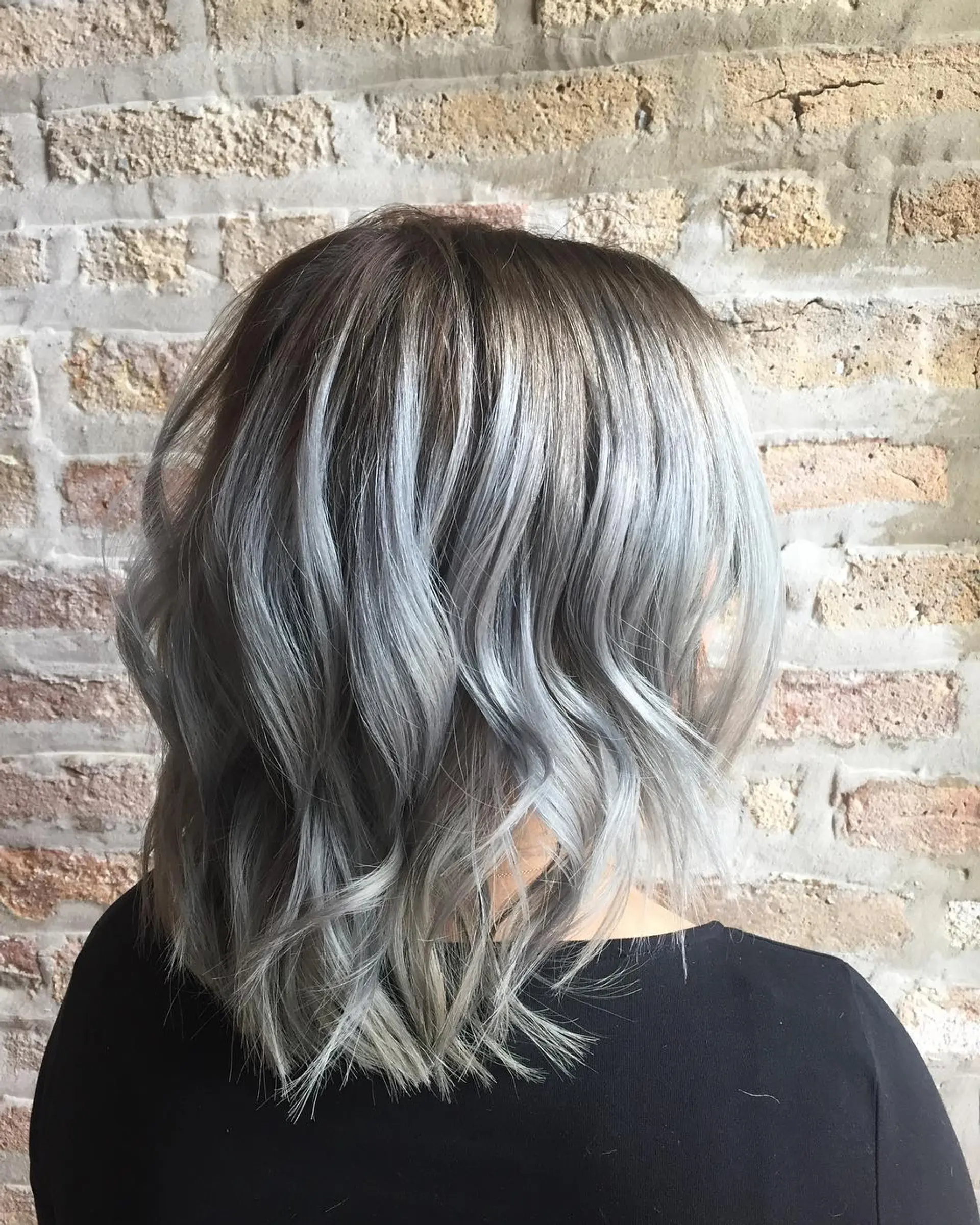 A trendy medium-length wavy hairstyle with icy silver and gray tones. 1