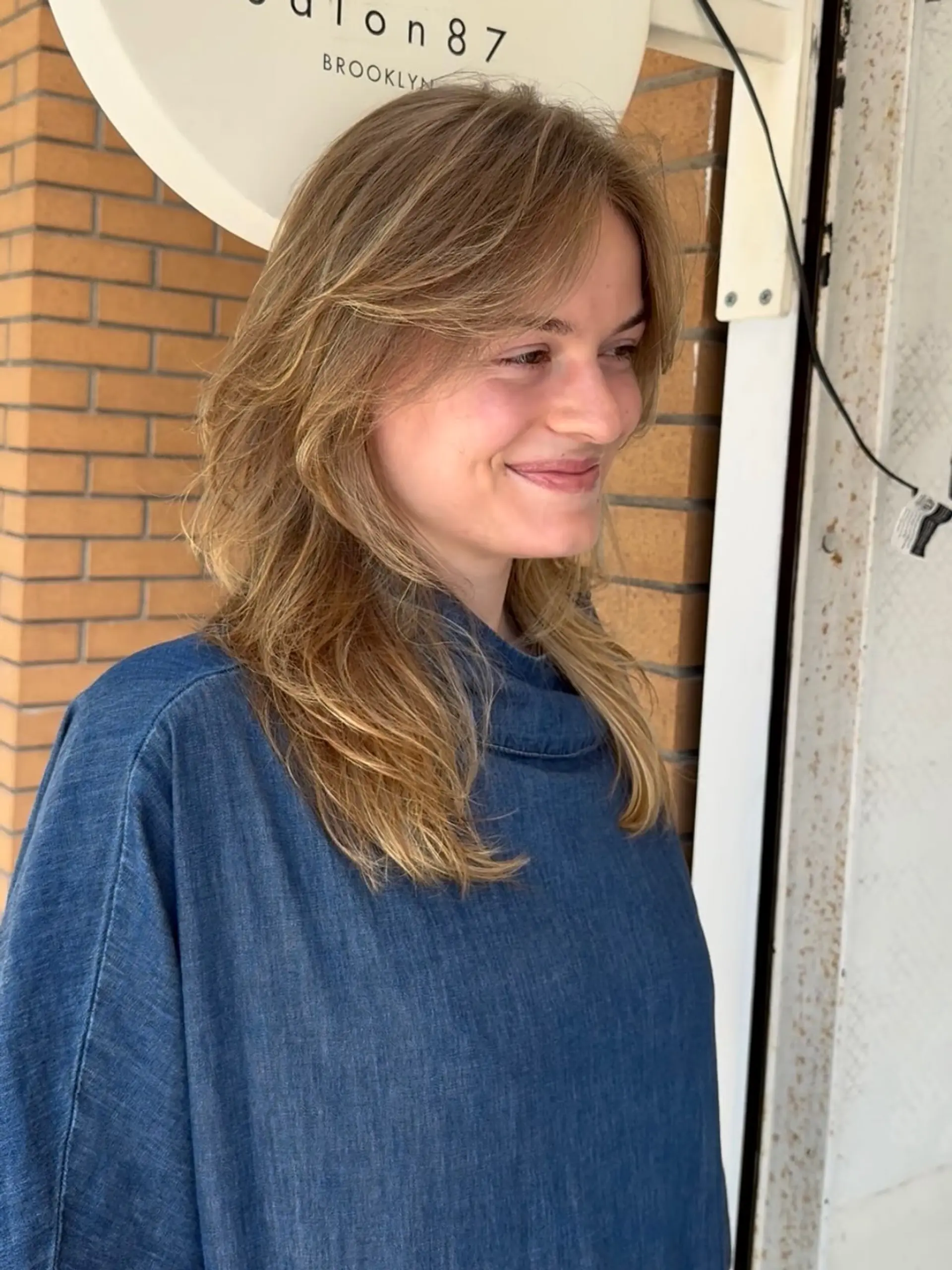 A medium-length layered haircut with soft, feathered ends and face-framing curtain bangs. 1