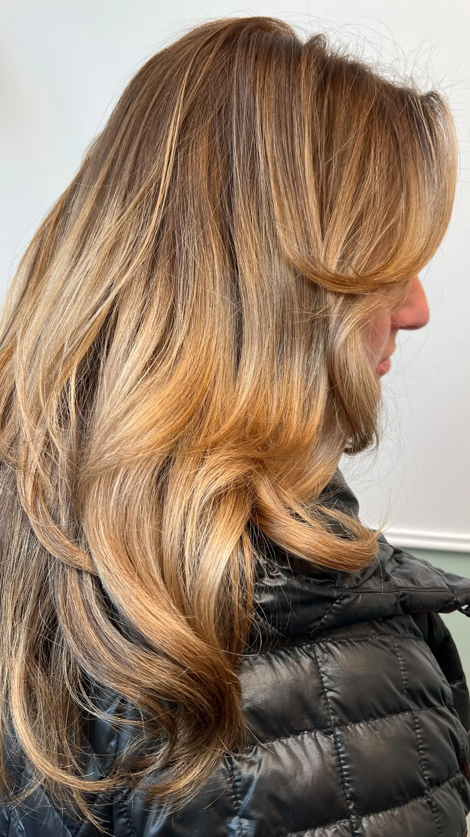 Long bronde hair featuring warm caramel and golden blonde highlights styled in smooth, voluminous layers. 1