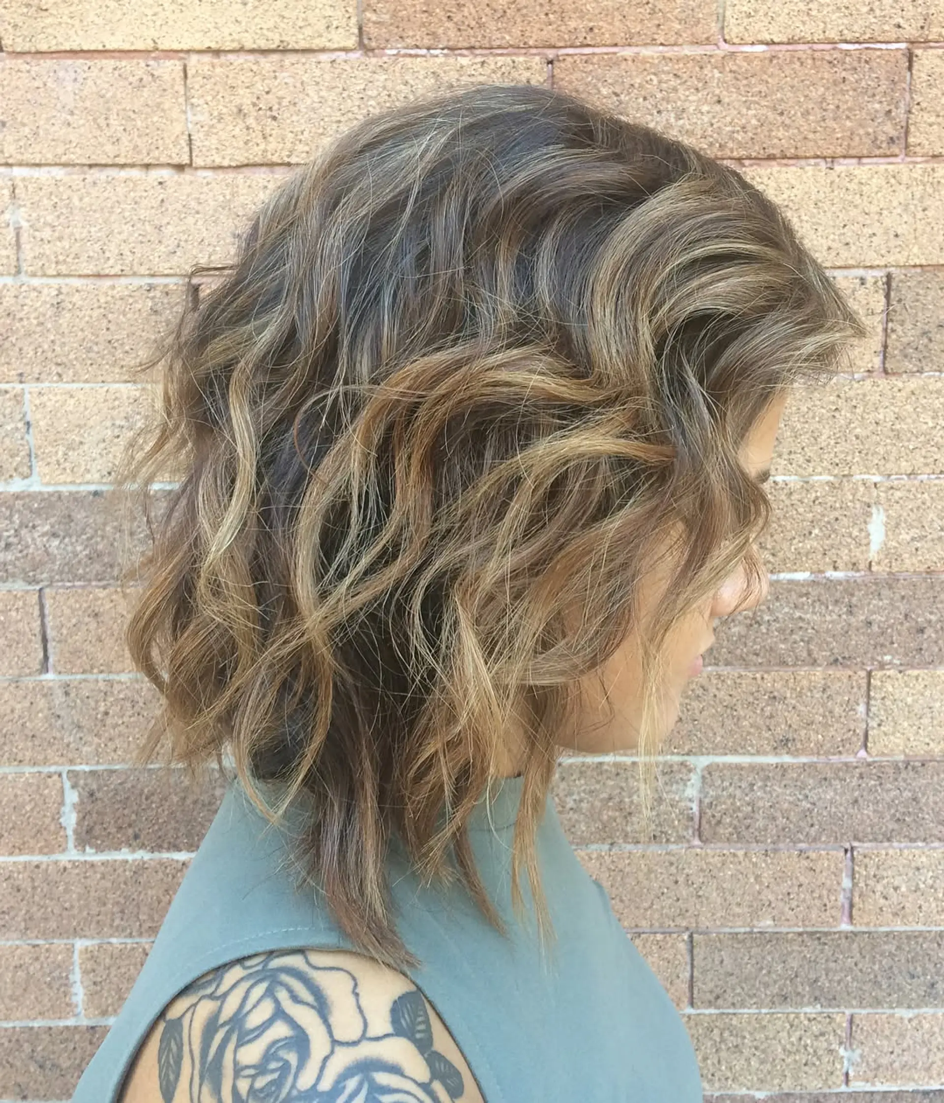 A wavy, medium-length hairstyle featuring a bronde balayage. 2