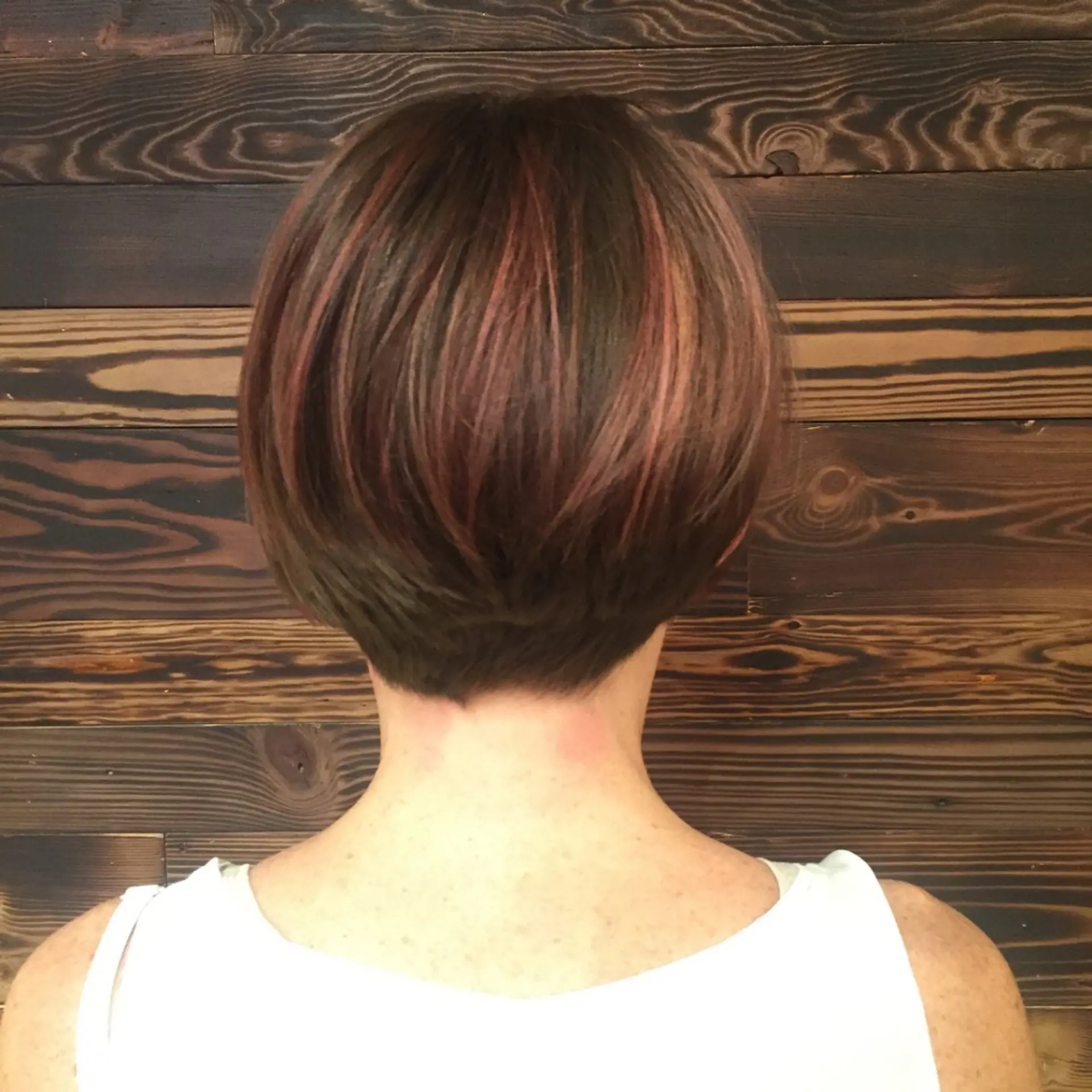 A modern asymmetrical bob haircut with vibrant pink highlights. 2