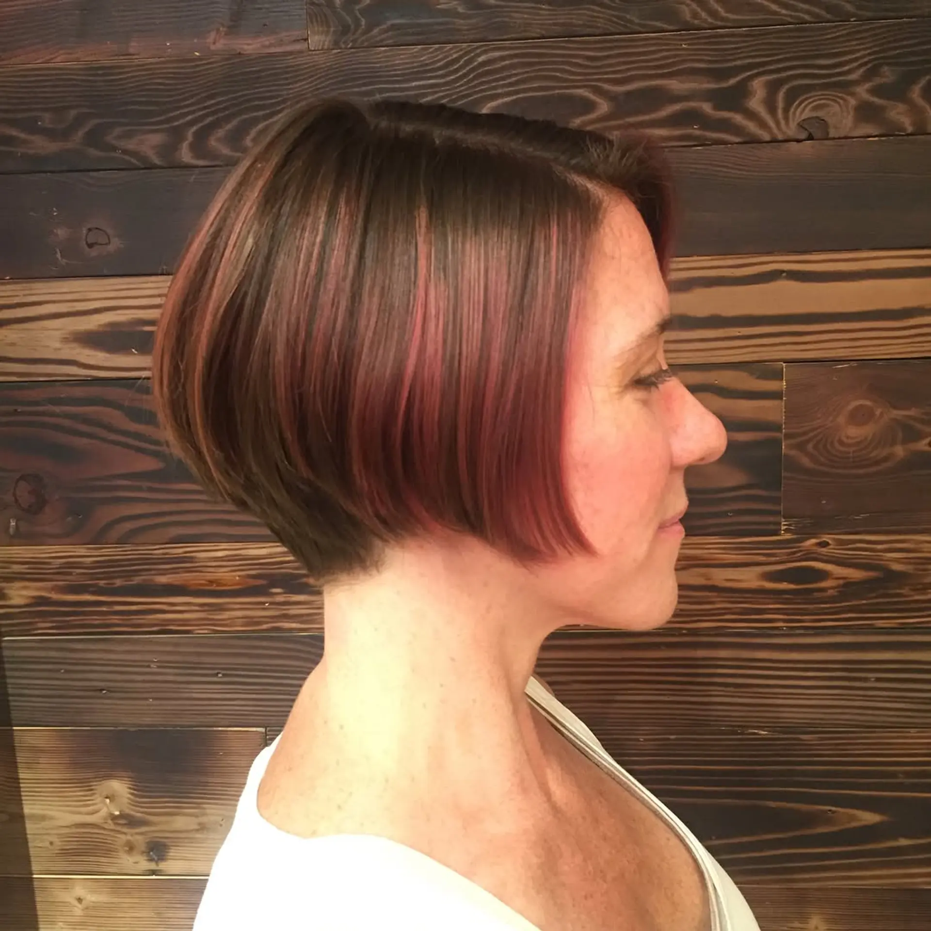 A modern asymmetrical bob haircut with vibrant pink highlights. 3