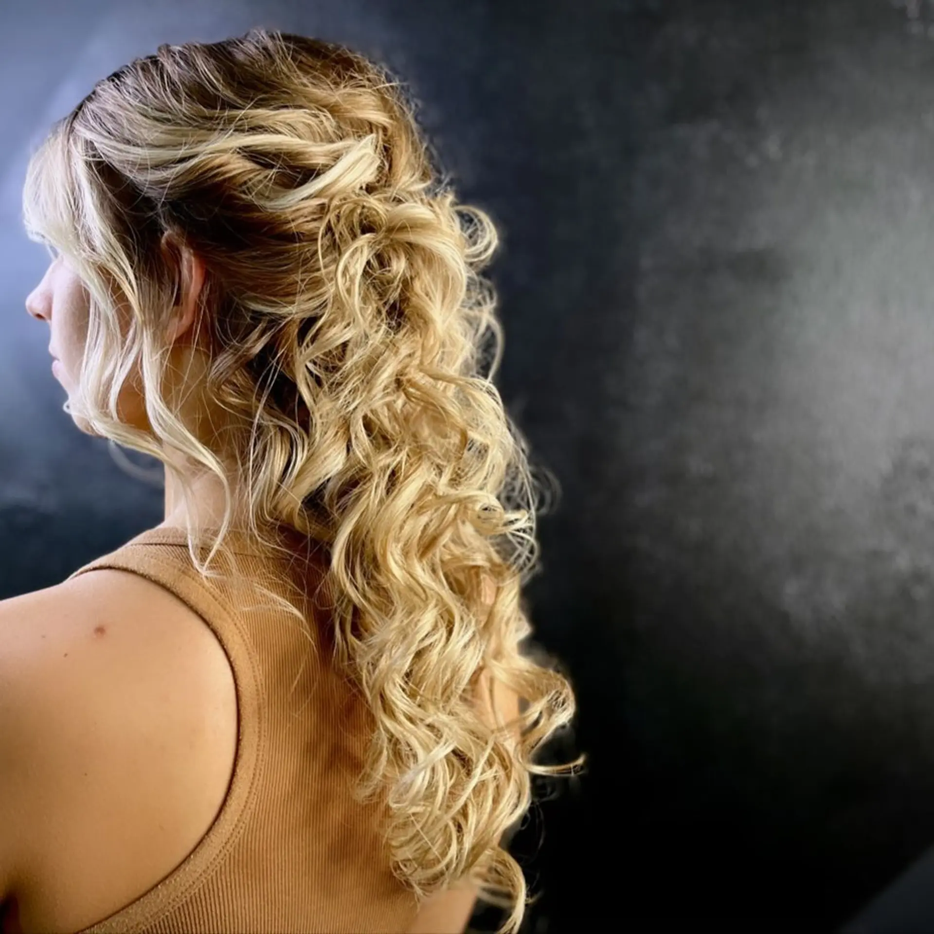 A romantic and stylish half-updo featuring soft, cascading curls and bangs. 1