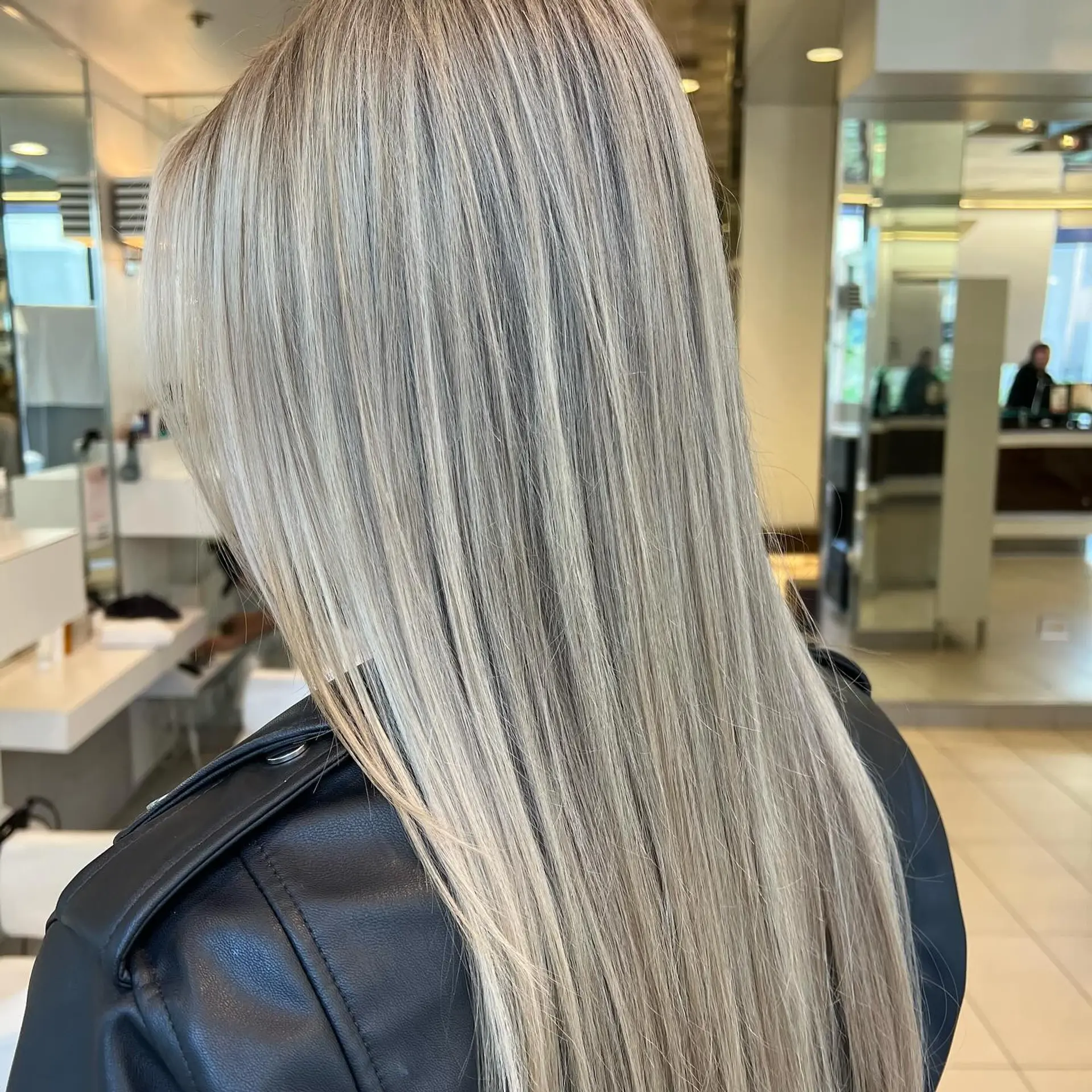 Long, sleek straight hair colored in a dimensional cool ash blonde with fine, blended highlights. 1