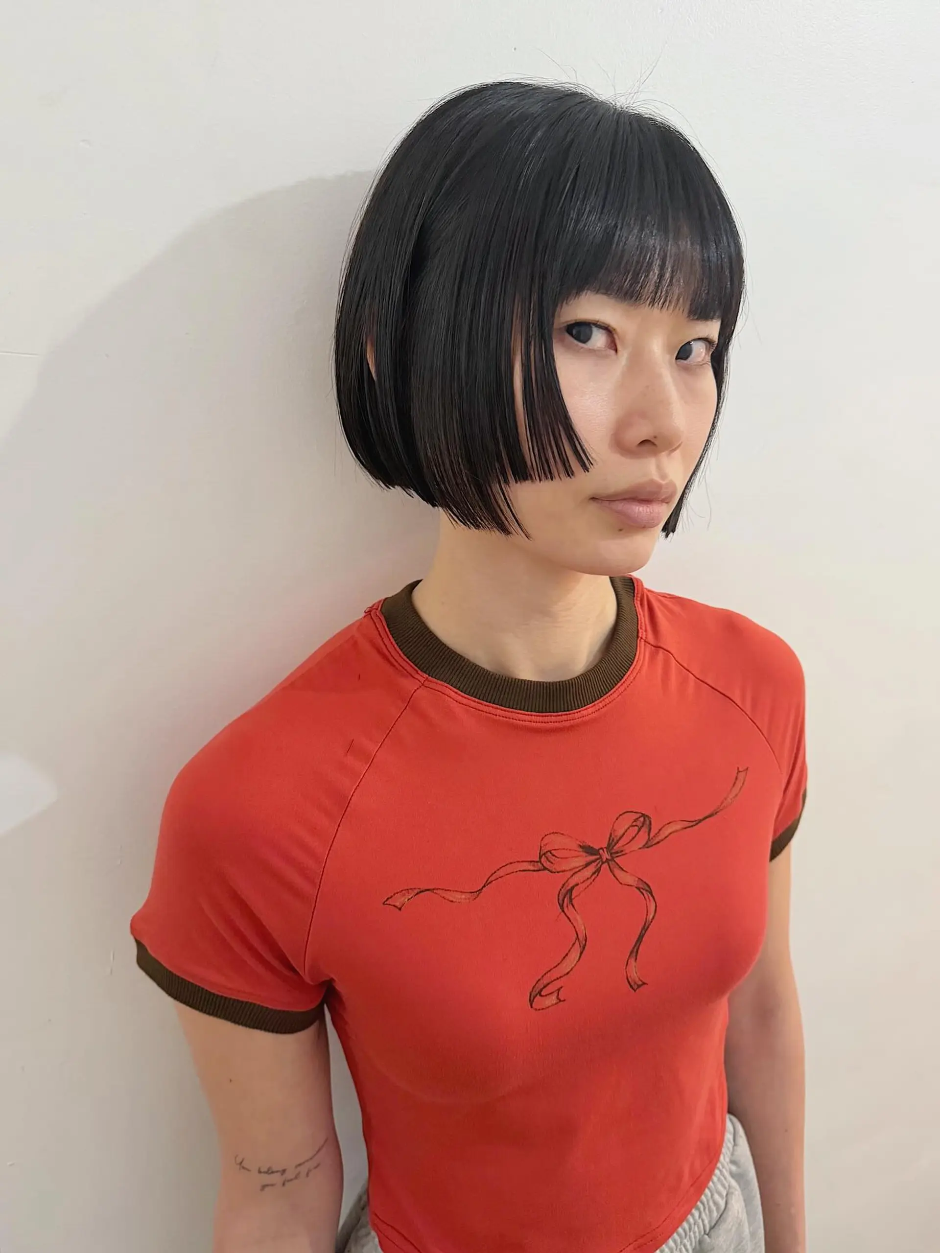 A sharp and modern chin-length bob featuring a precise blunt cut and trendy micro bangs that create a bold, graphic aesthetic. The face-framing sections add an edgy touch to the classic bob. 1