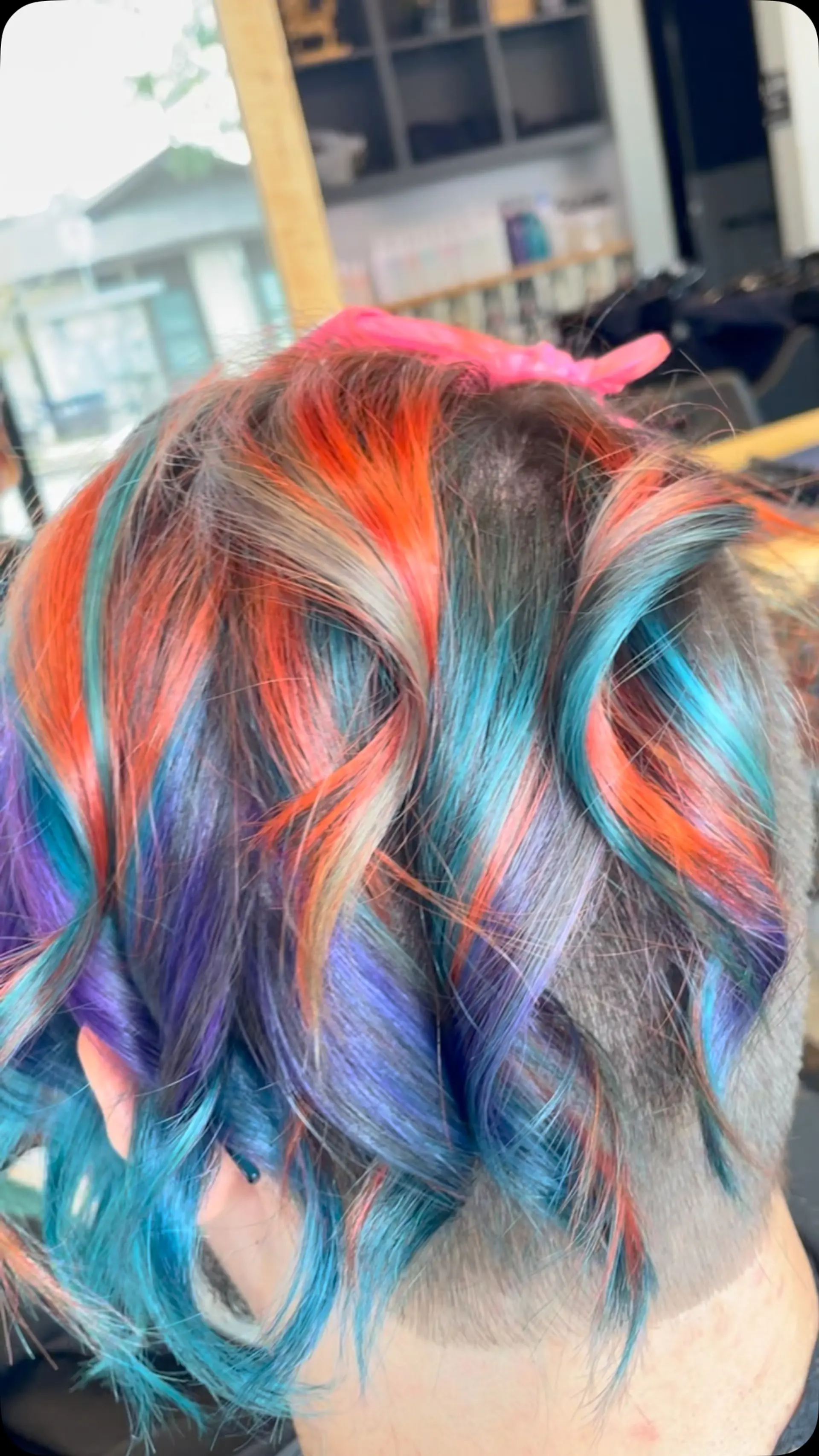 Short wavy hair featuring vivid rainbow panels of orange, teal, blue, and purple over a shaved undercut. 1