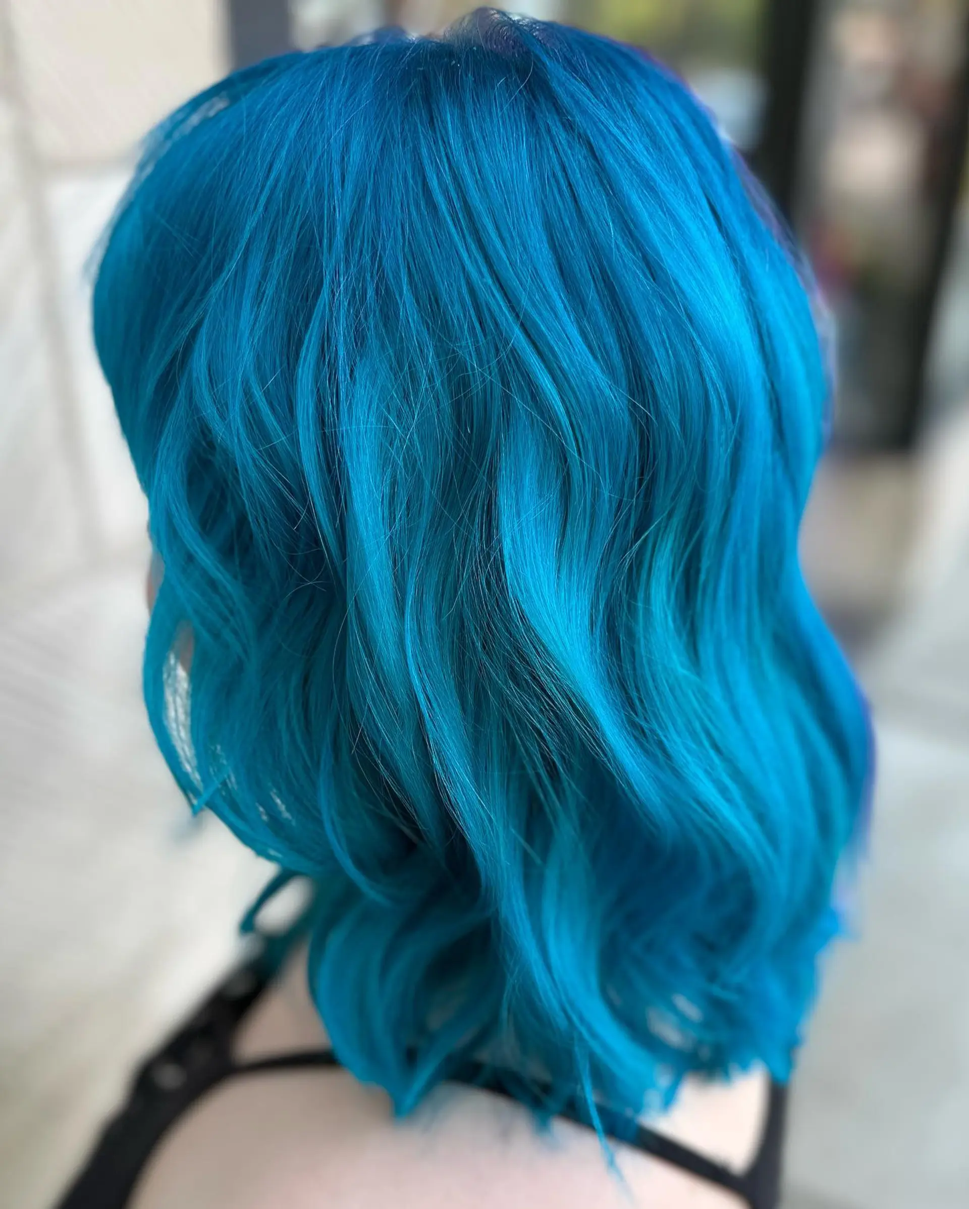 Vibrant all-over electric cyan-blue medium-length cut styled in loose, textured waves. 1