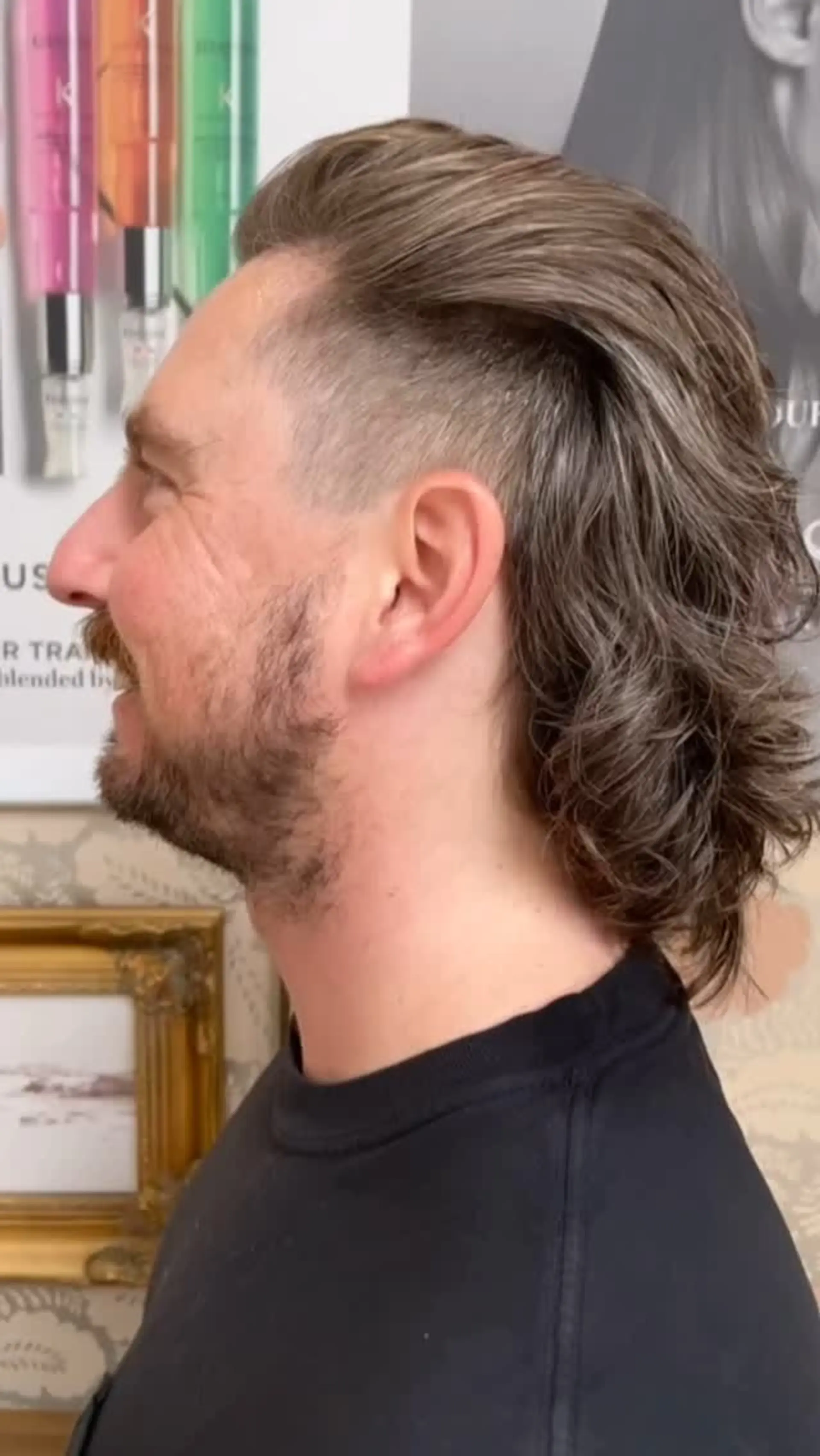 A modern wavy mullet haircut featuring buzzed undercut sides and swept-back length through the top and nape. 1