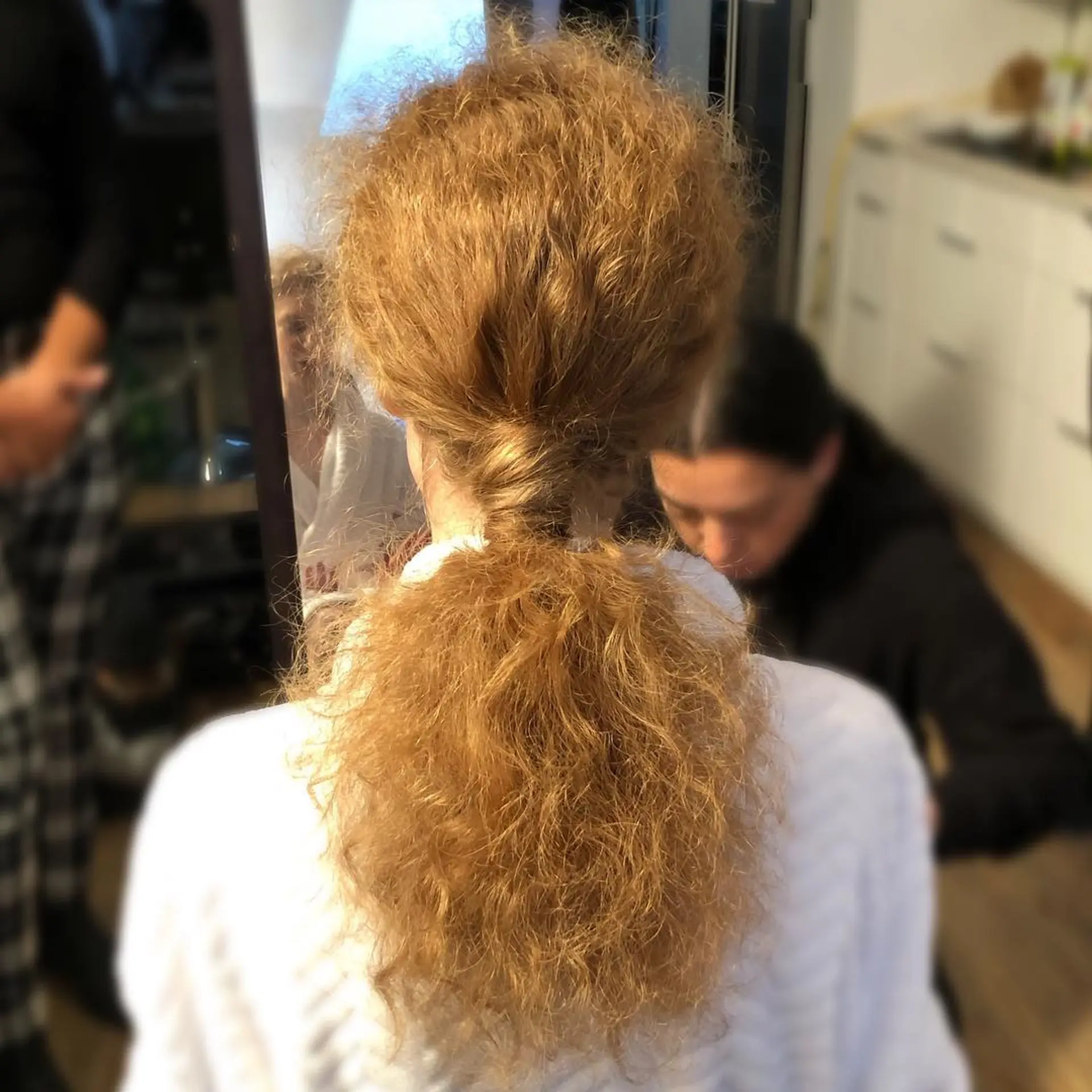 A textured low ponytail gathered at the nape of the neck with a strand wrapped around the base. 1