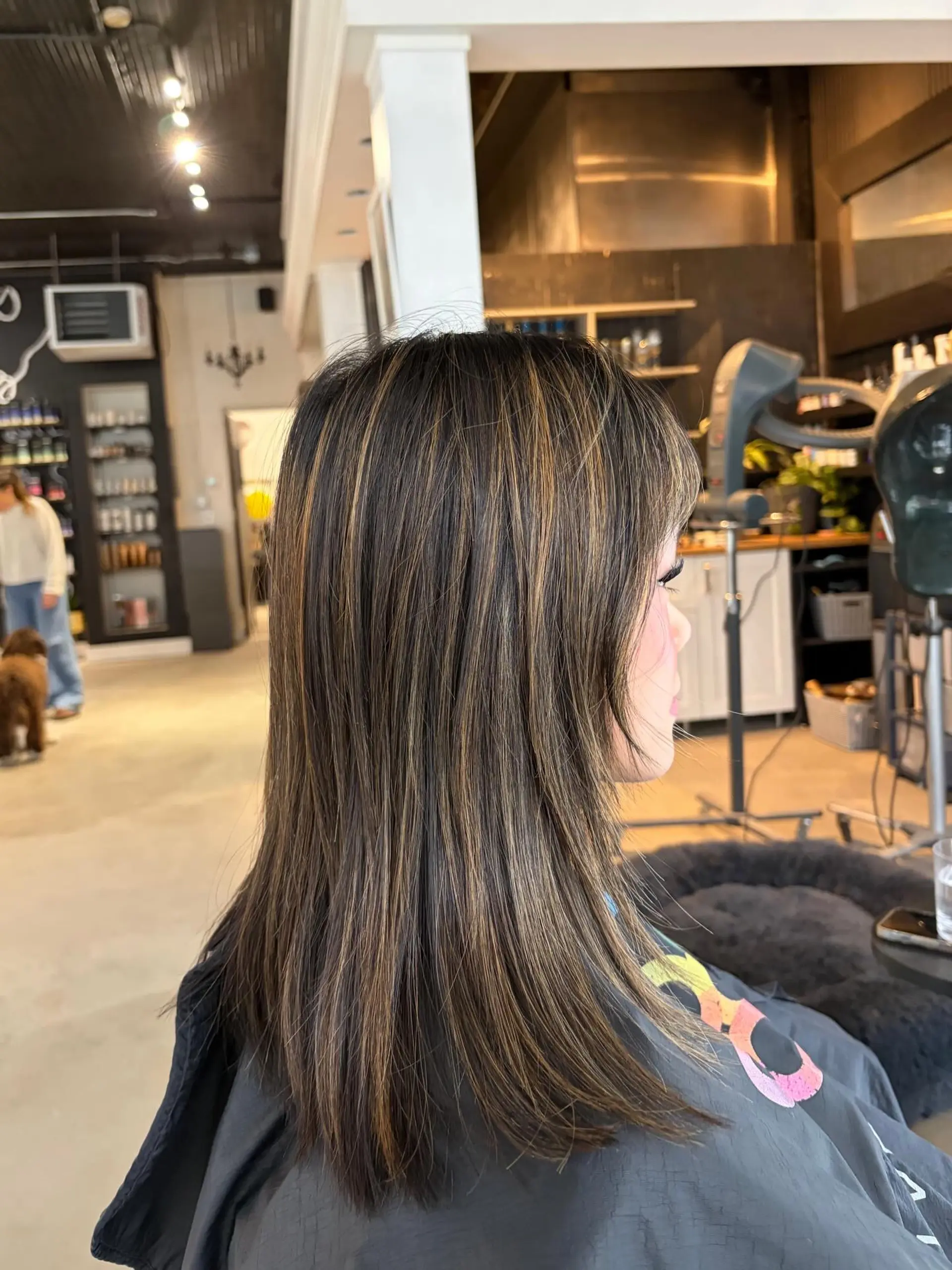 Straight, medium-length dark brown hair featuring finely blended warm caramel highlights and soft face-framing layers. 1