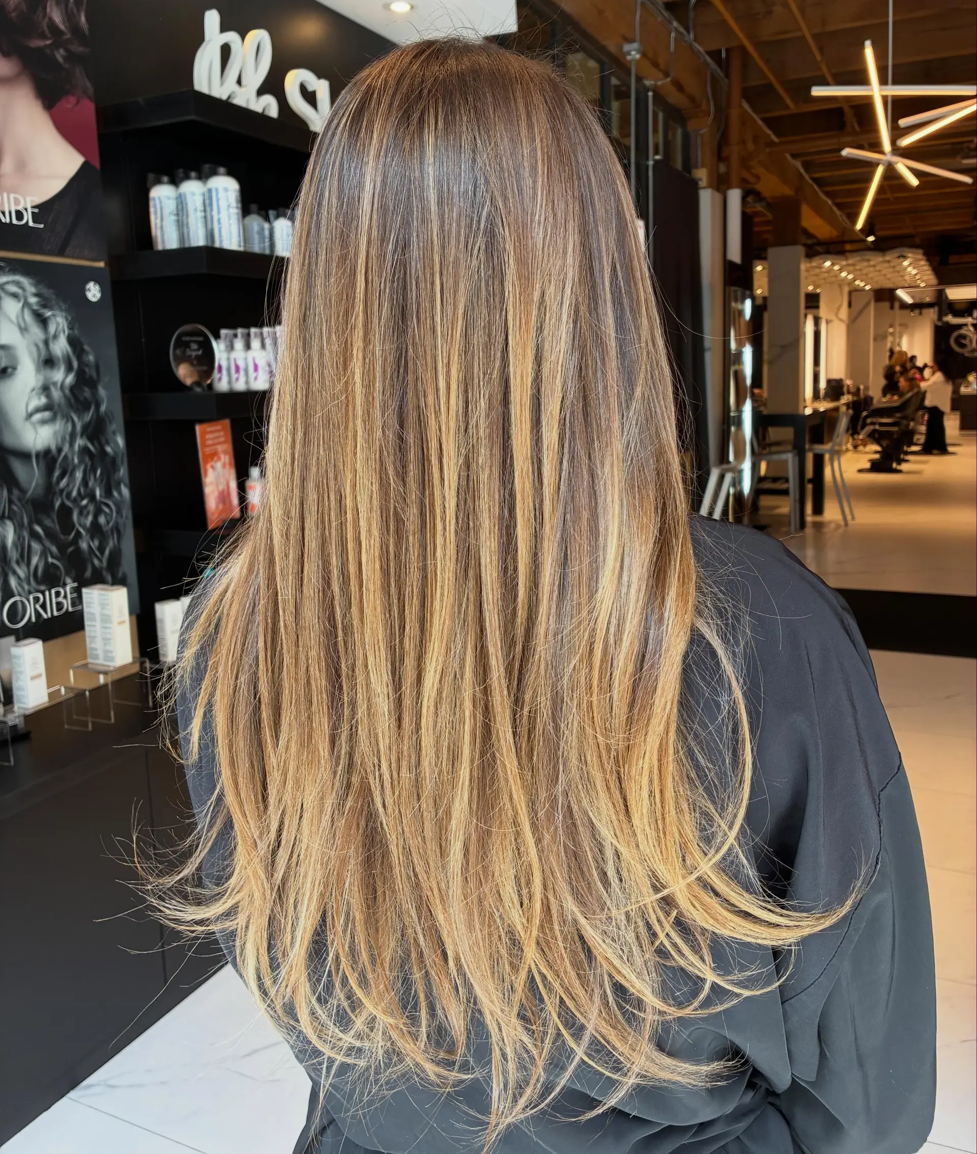 Long straight brunette hair blended with warm honey and caramel balayage highlights. 1