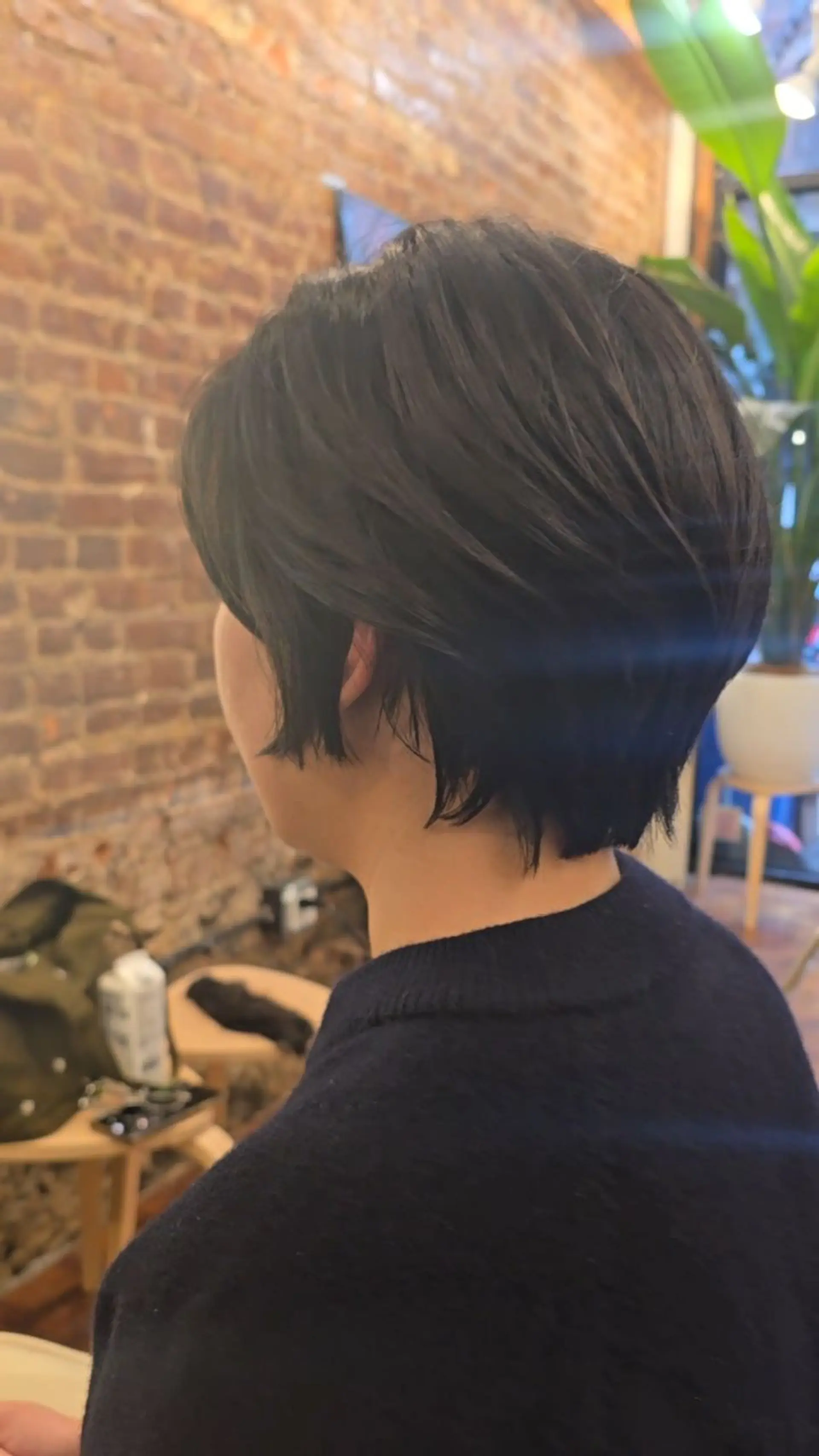 A short, layered bixie cut with textured ends tapering around the nape and ear. 1