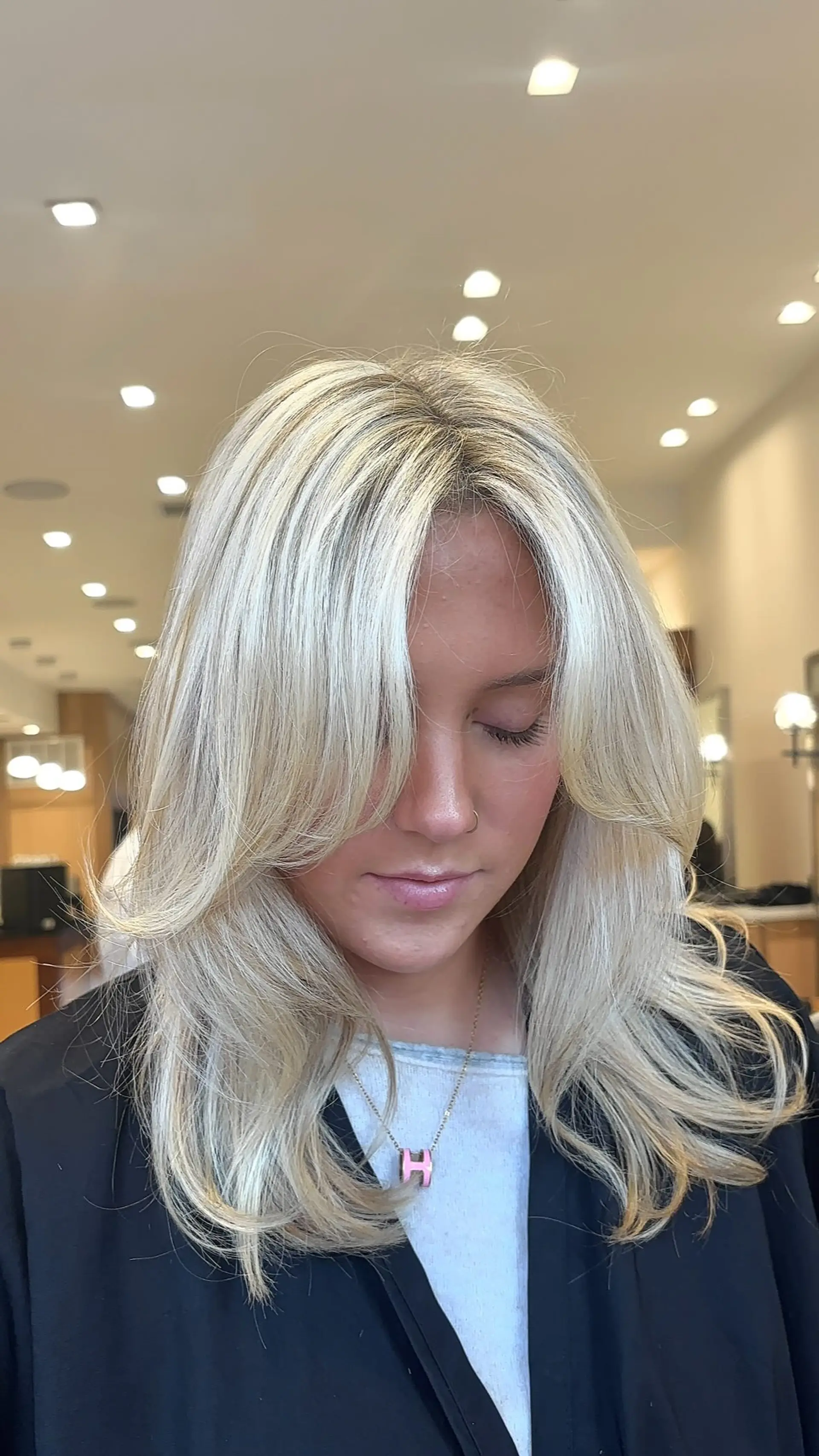 Bright dimensional blonde styled with curtain bangs, soft face-framing layers, and a bouncy blowout. 1