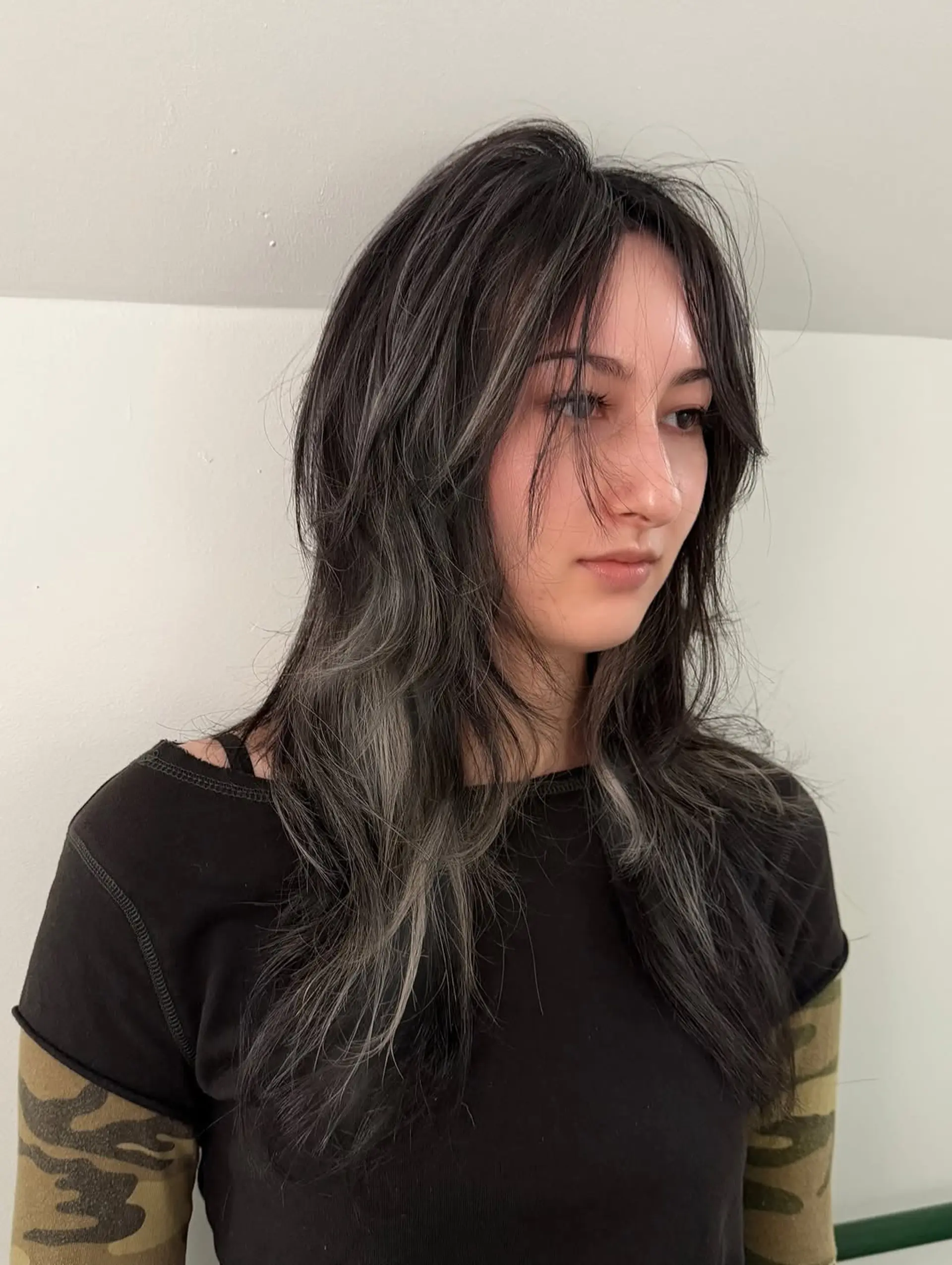 A layered, textured shag haircut featuring wispy curtain bangs that frame the face, giving it a soft yet edgy, modern silhouette. 1