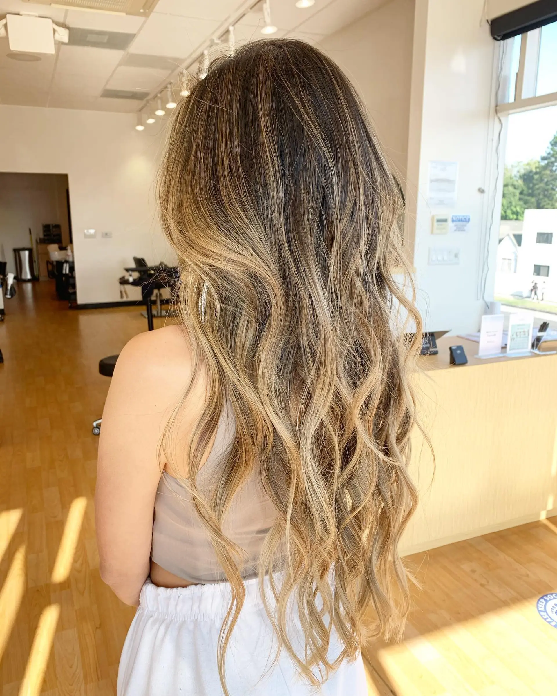 Long hair styled into loose, effortless waves with blended honey and light blonde highlights over a dark brown base. 1