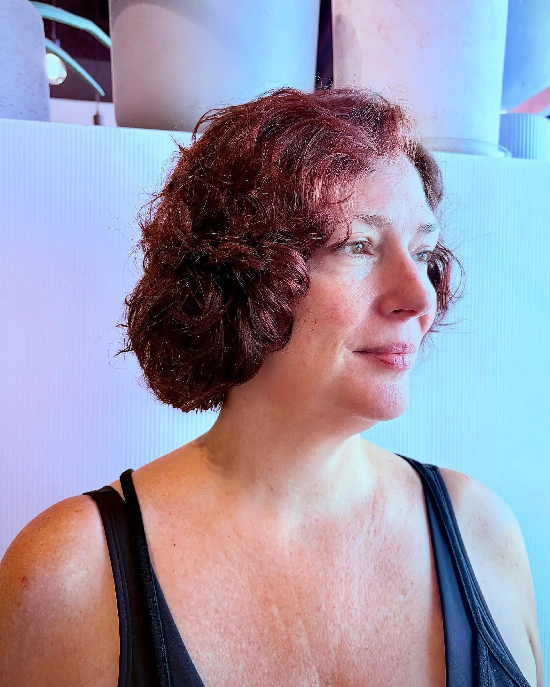 A chin-length curly bob featuring softly defined curls and rich auburn tones. 1