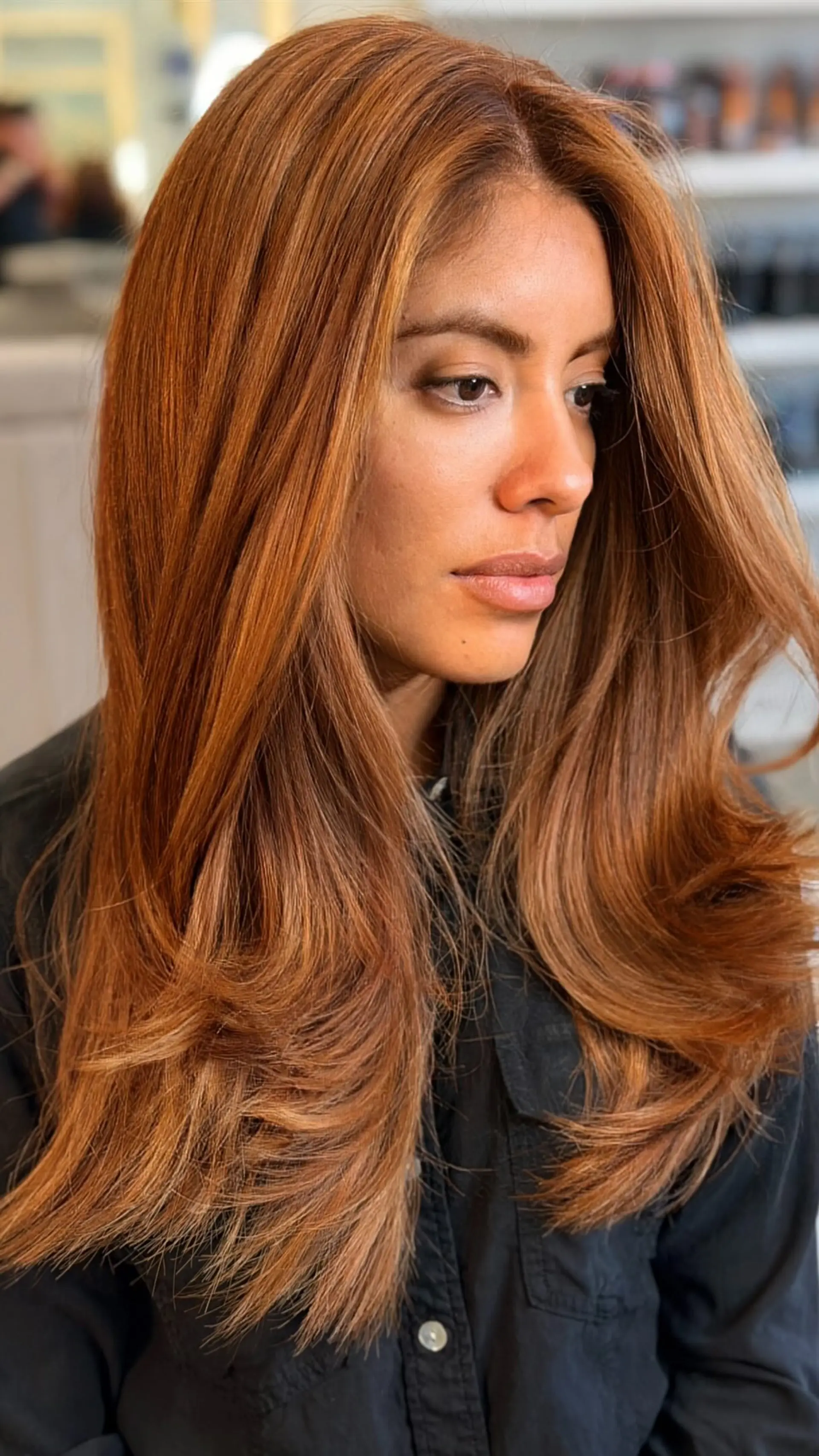 Long, warm copper hair styled in a voluminous blowout with curved, layered ends. 1