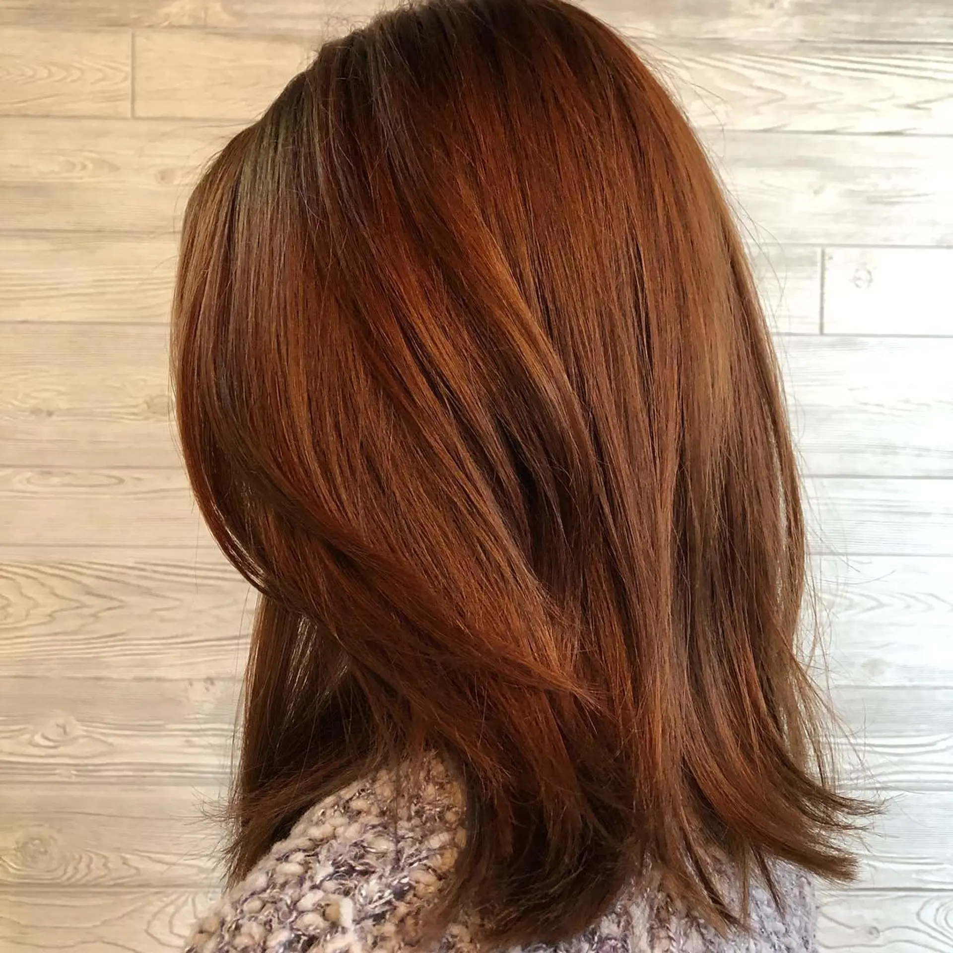 Medium-length warm auburn hair styled straight with soft layered ends and a smooth blowout finish. 1