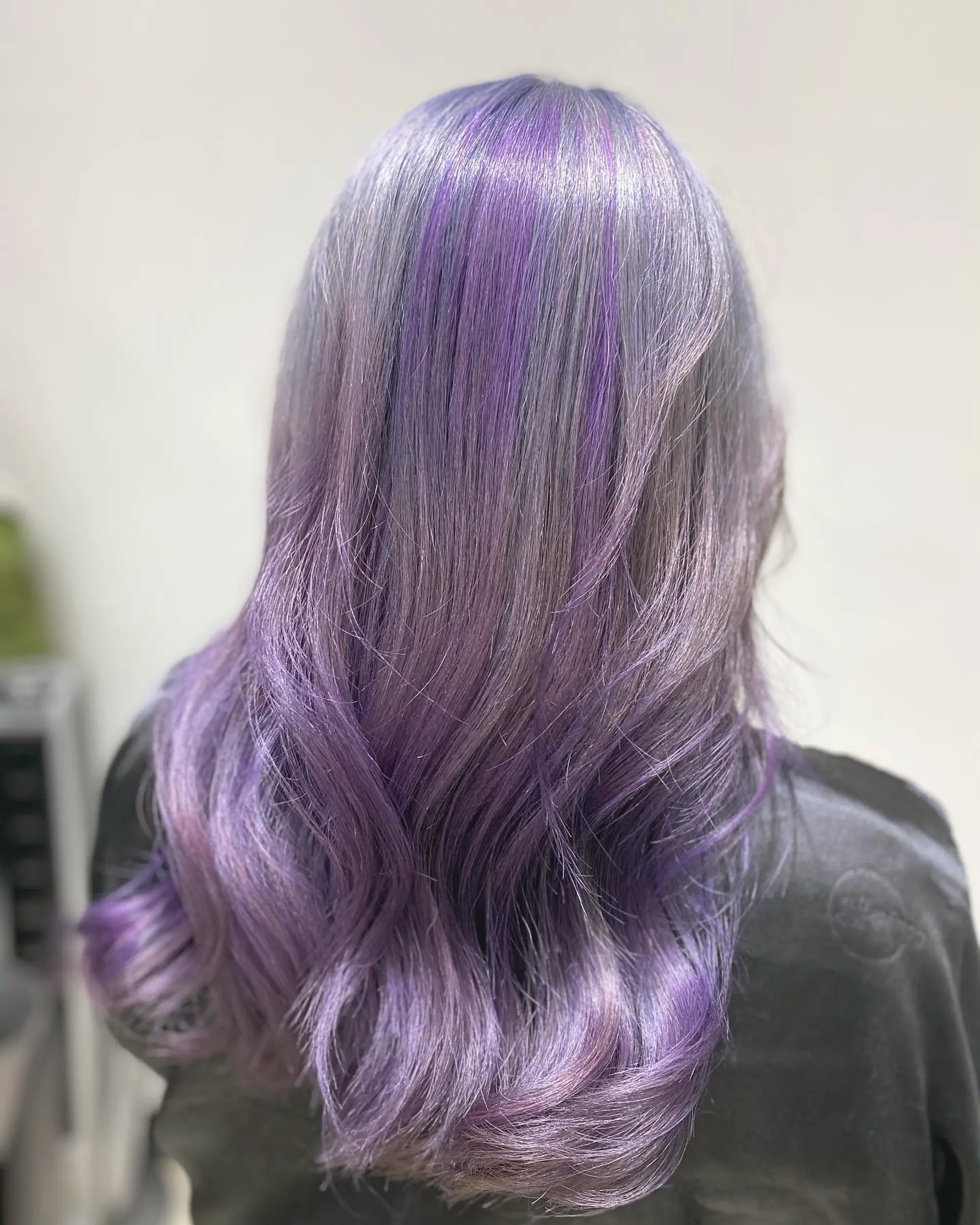 Long, wavy hairstyle with lavender roots that blend into purple ends. 2