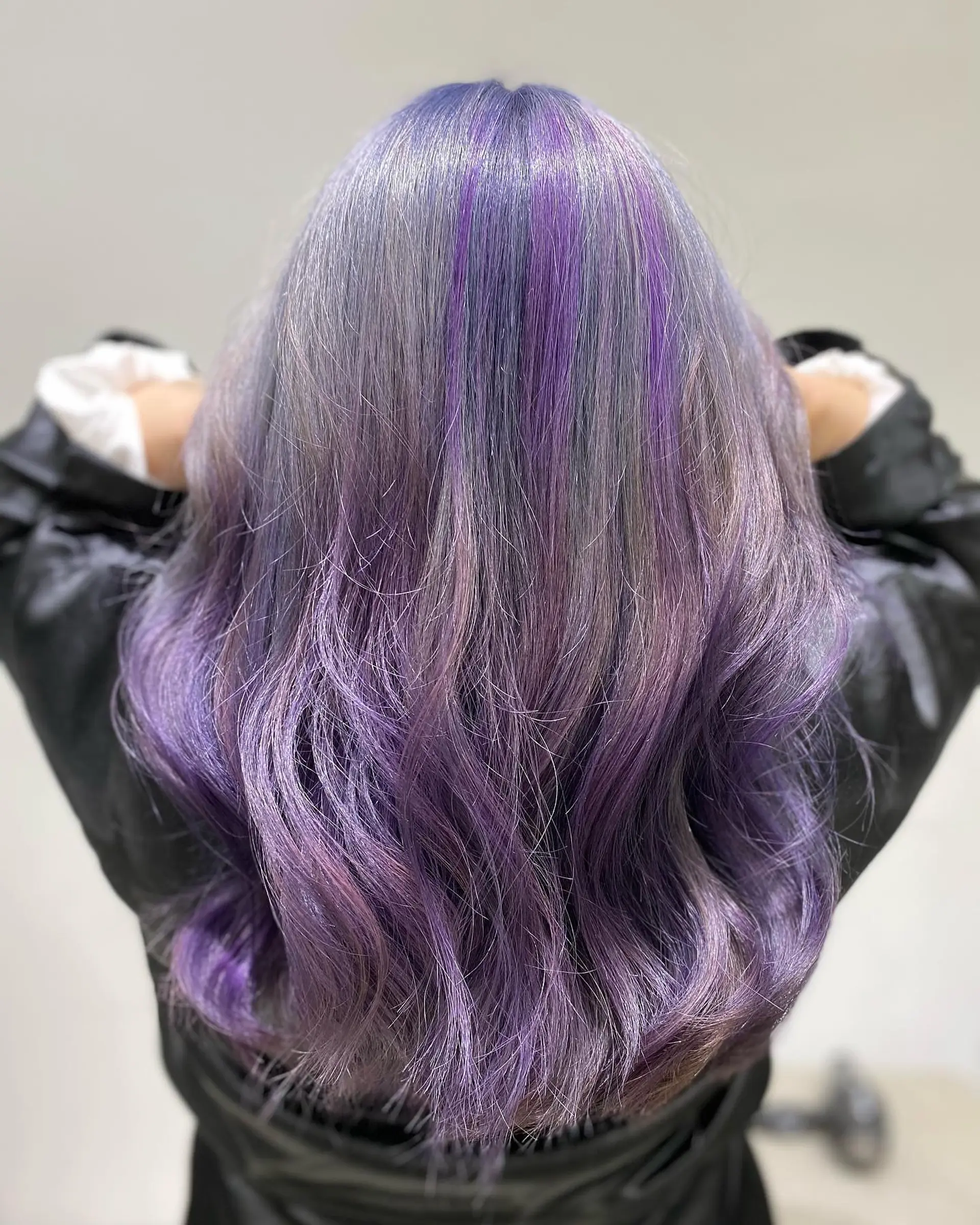 Long, wavy hairstyle with lavender roots that blend into purple ends. 3