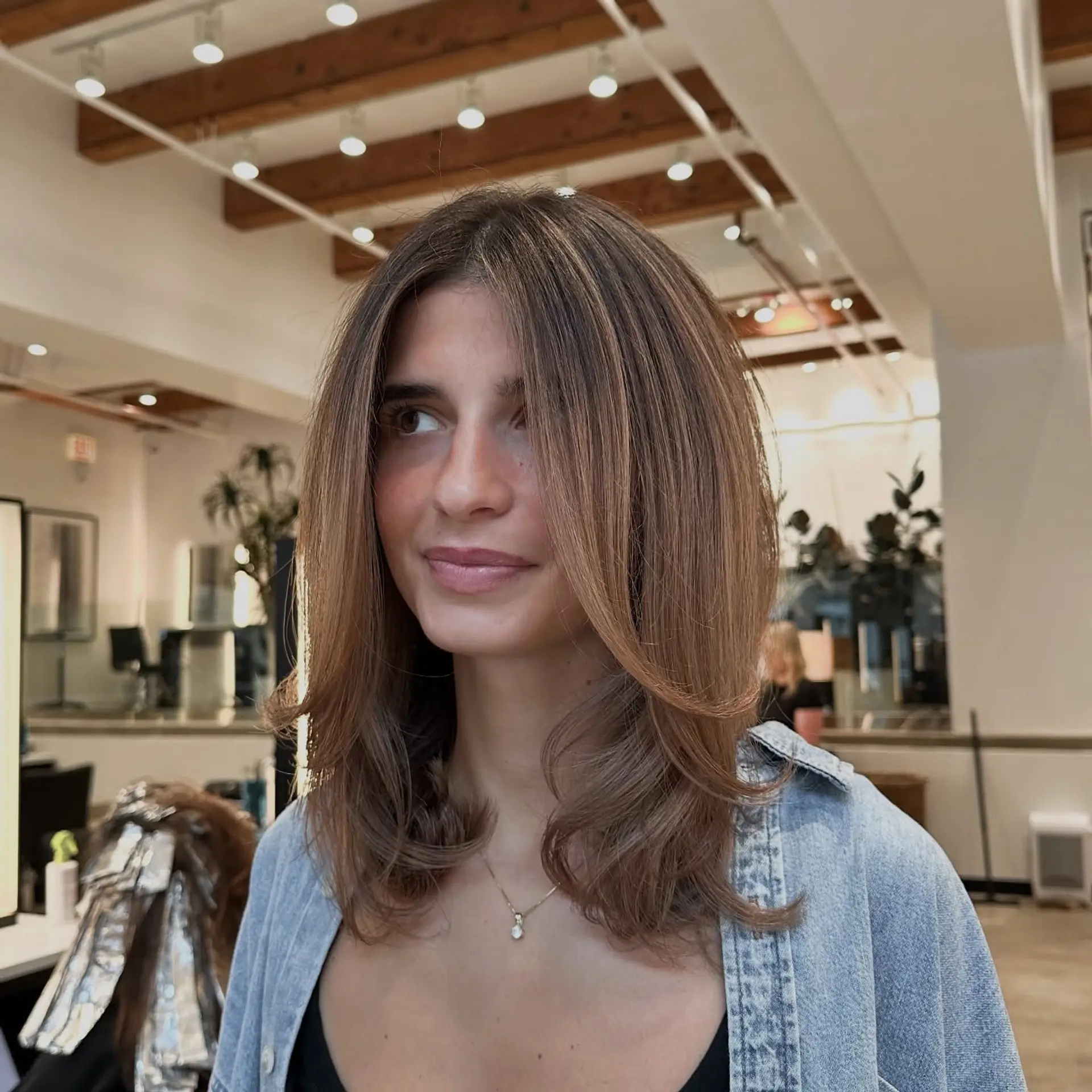A bronde colored medium length haircut with subtle layers and face framing. 1