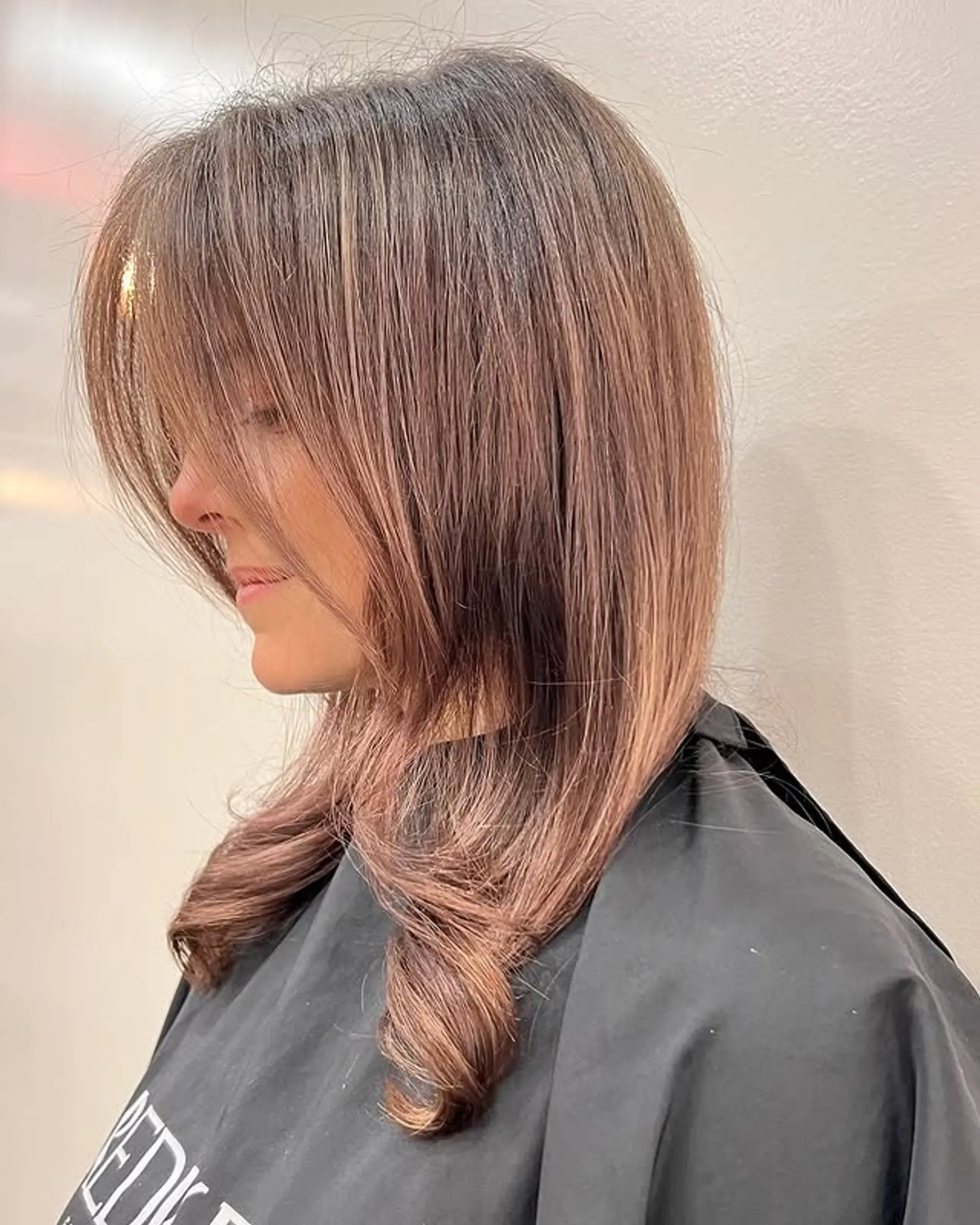 A medium-length layered bob with face-framing layers and curtain bangs. The style is soft and romantic. 1