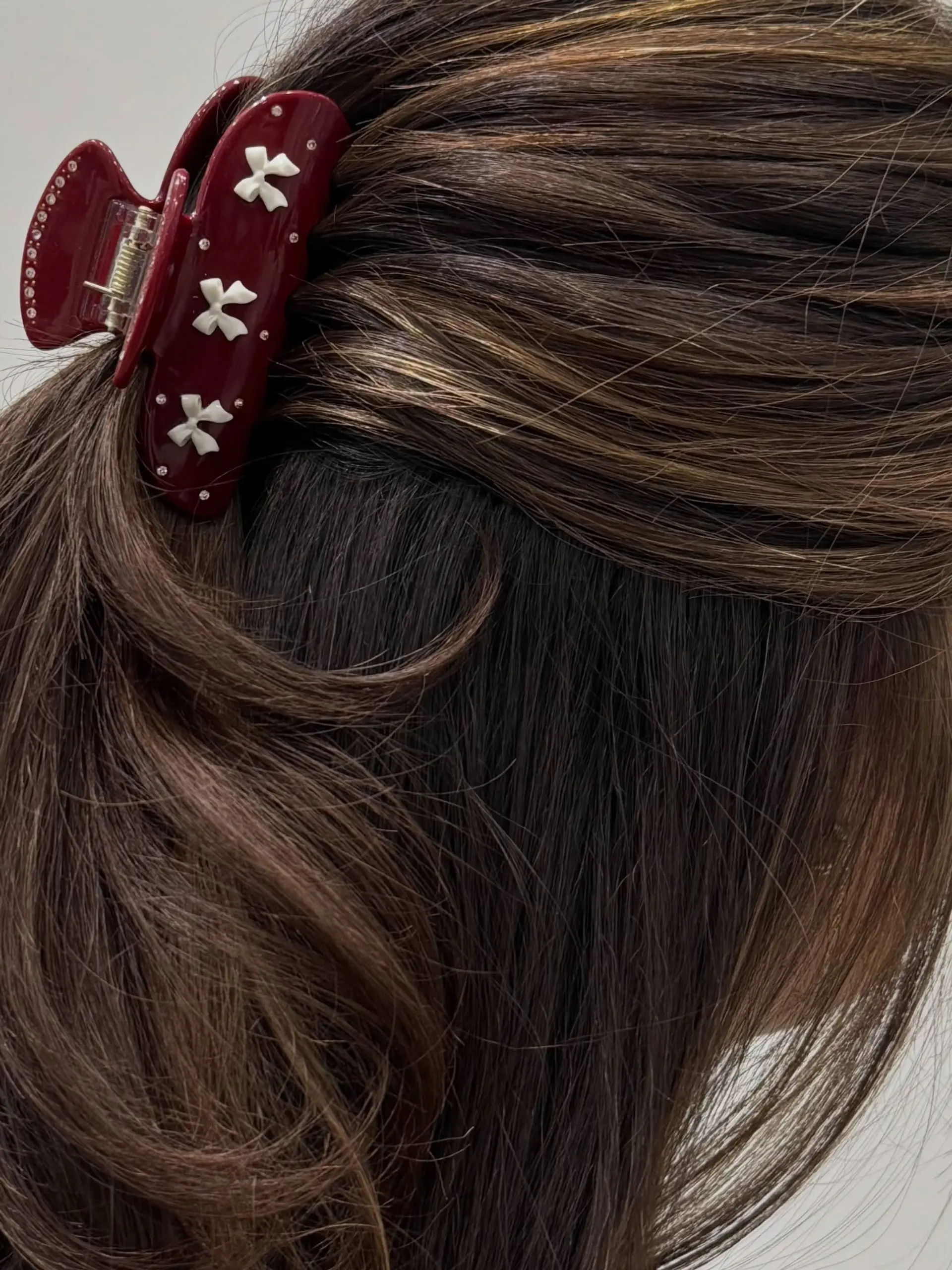 A dimensional deep brunette hairstyle styled softly and secured in a half-up clip with a decorative claw clip. 1