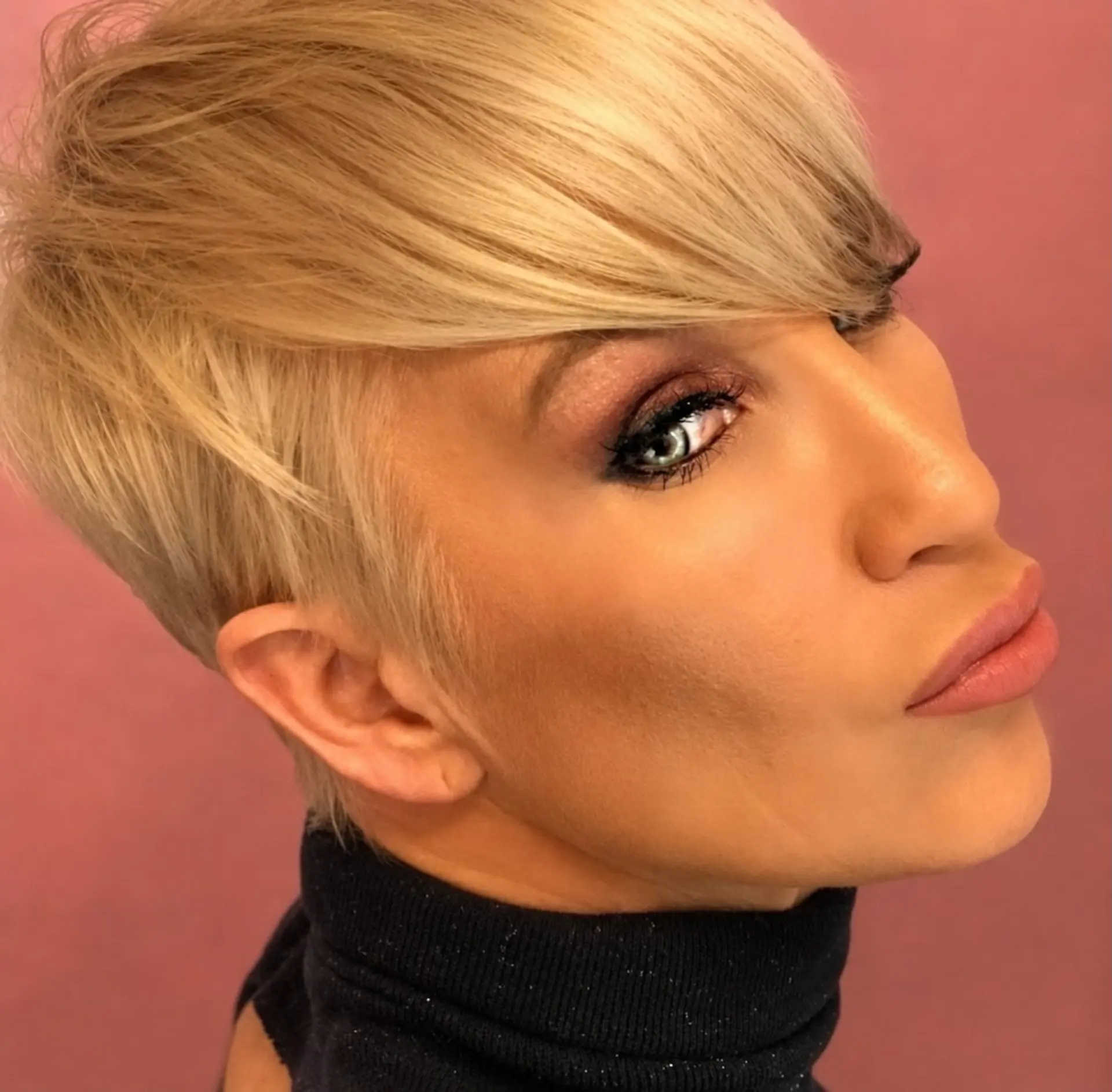A sleek, modern pixie cut featuring tapered sides and long, sweeping fringe in a clean blonde tone. 1