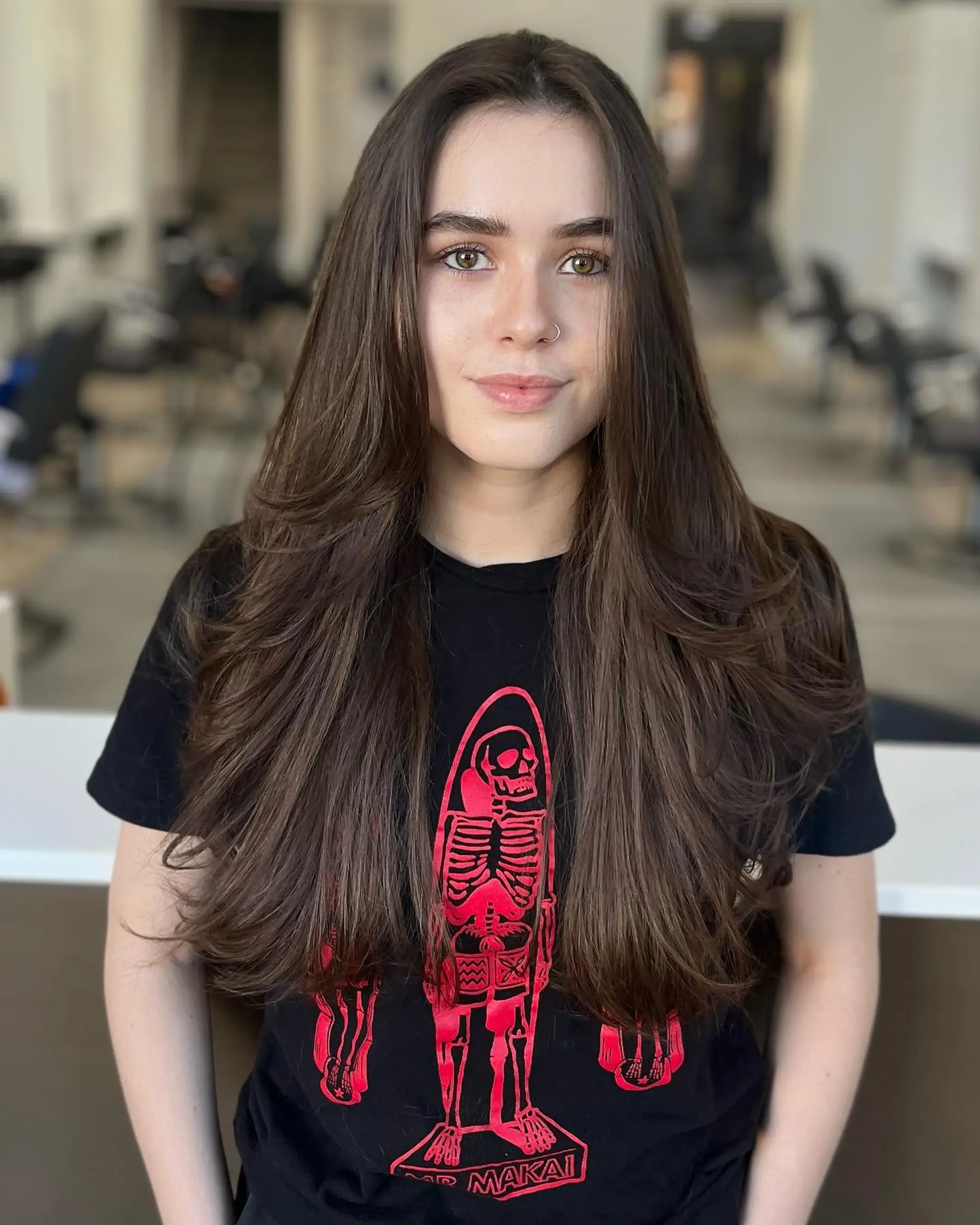 Long dark brown hair cut with soft, cascading layers and styled into a voluminous round-brush blowout. 1