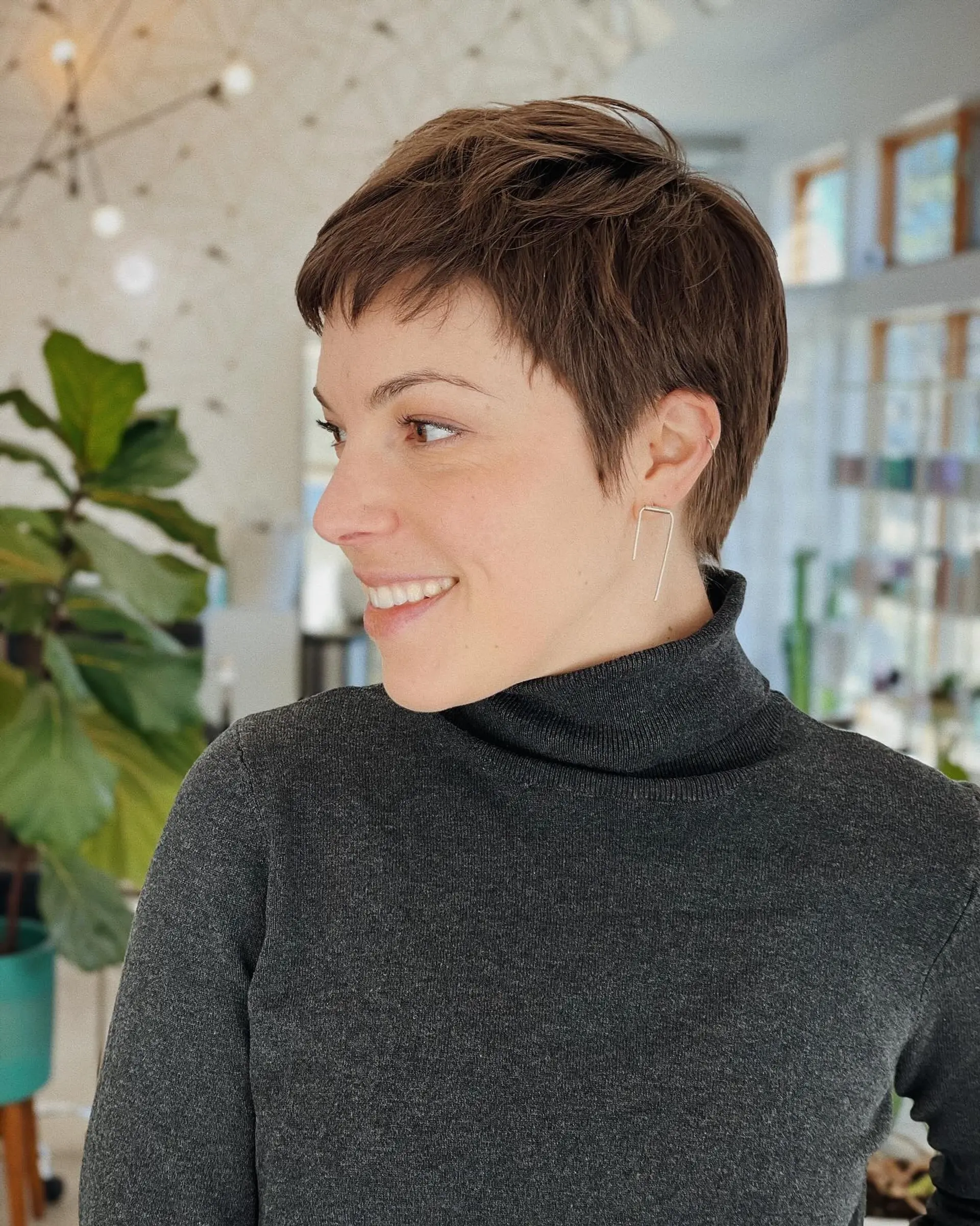 A textured scissor-cut pixie featuring soft micro-bangs and tapered sides contouring the ears. 1