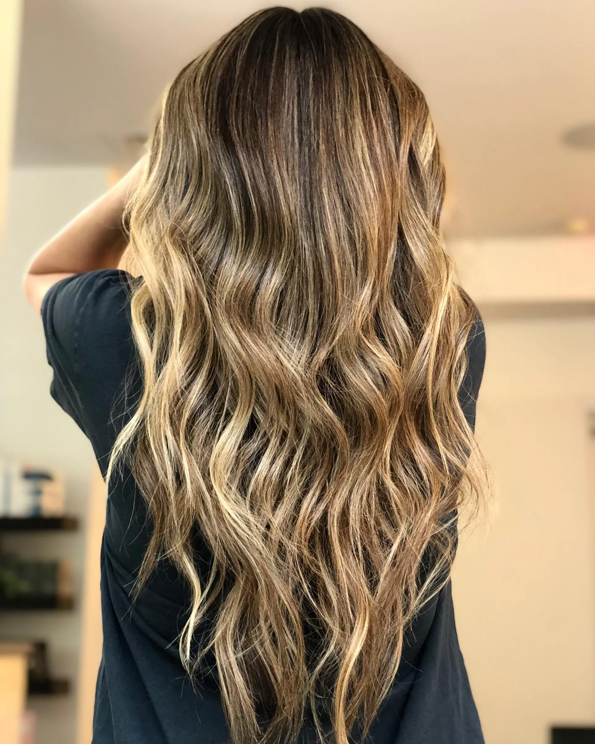 Long cascading waves featuring blended babylights and golden blonde balayage over a rich brunette base. 1
