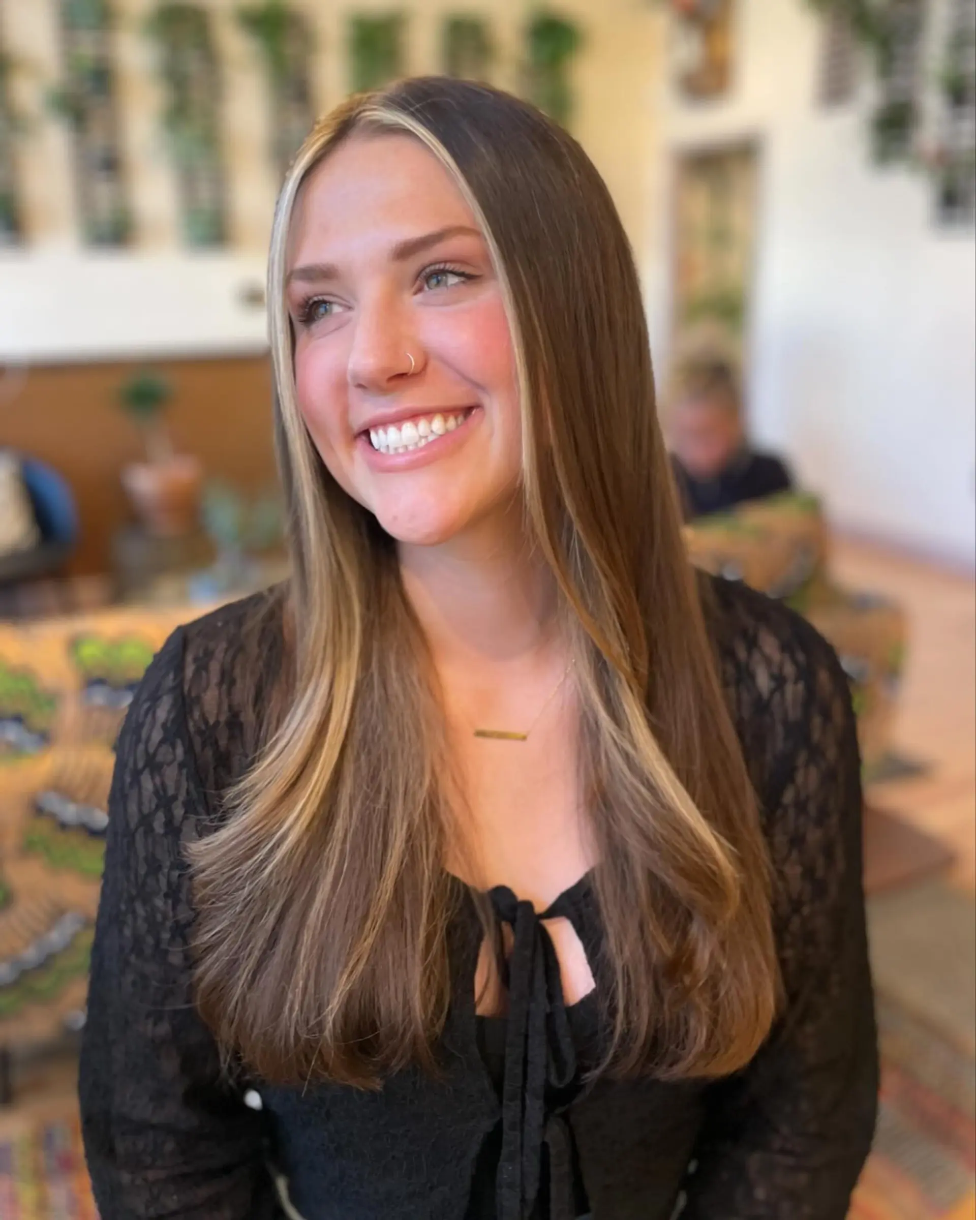 Long straight brunette hair cut with soft layers and accented by a bold, bright blonde money piece framing the face. 1