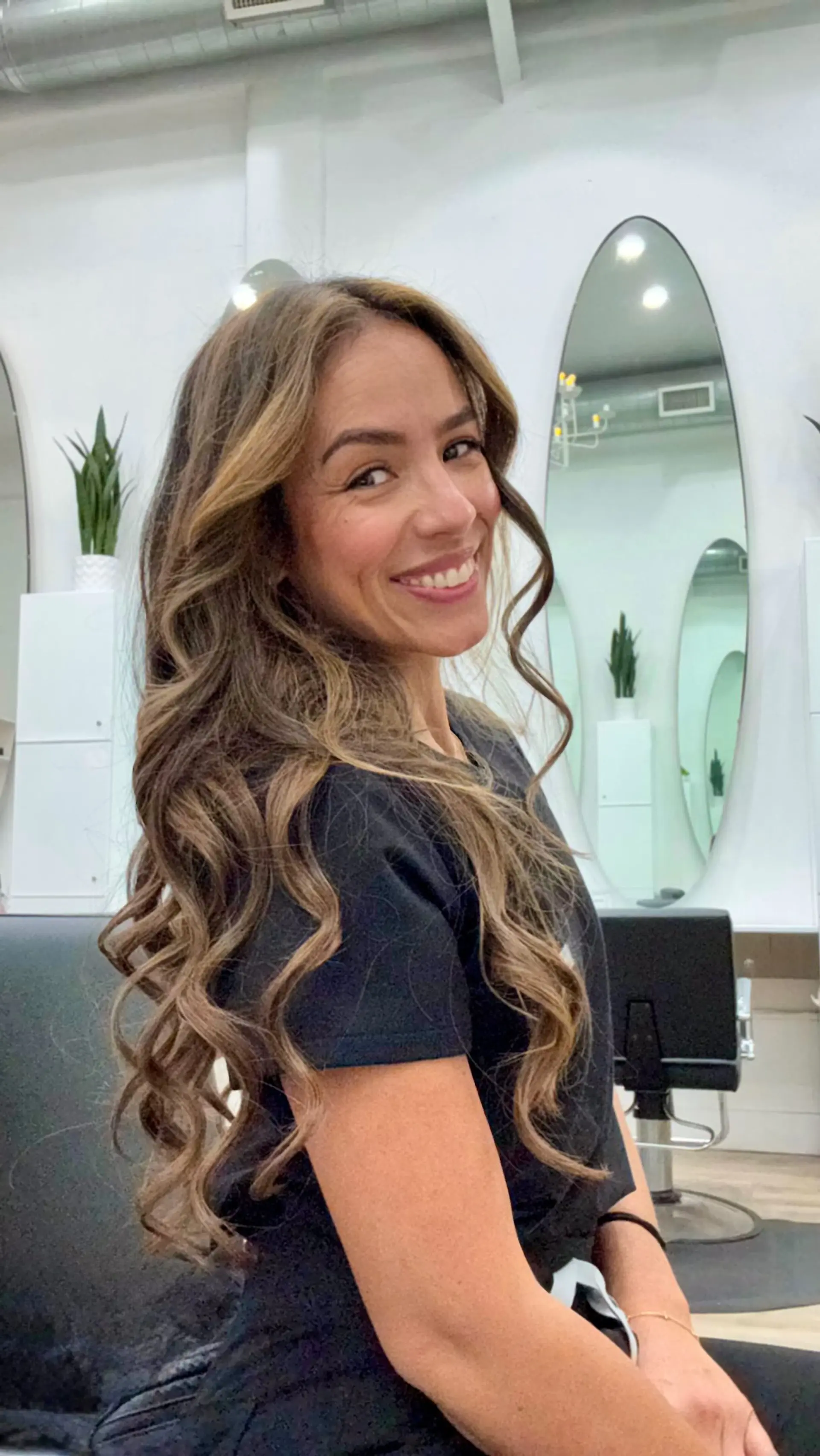 Long brown hair styled in defined cascading waves with warm caramel balayage highlights. 1