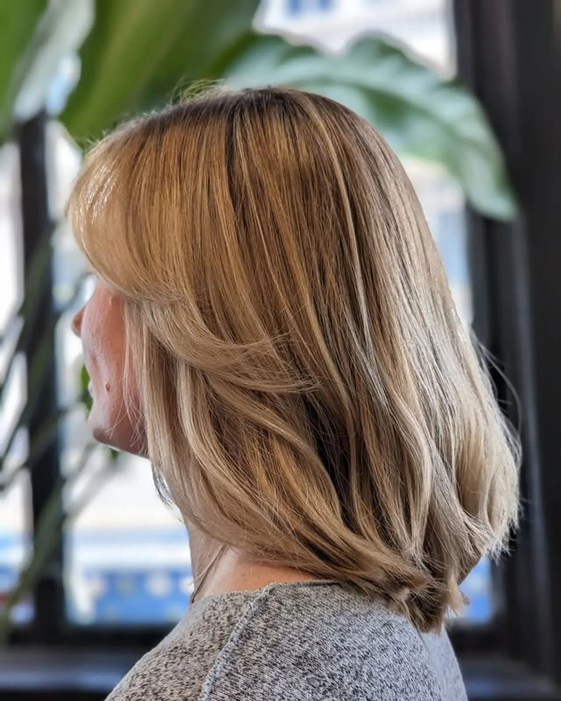 A medium-length layered haircut with beachy waves and curtain bangs. 1