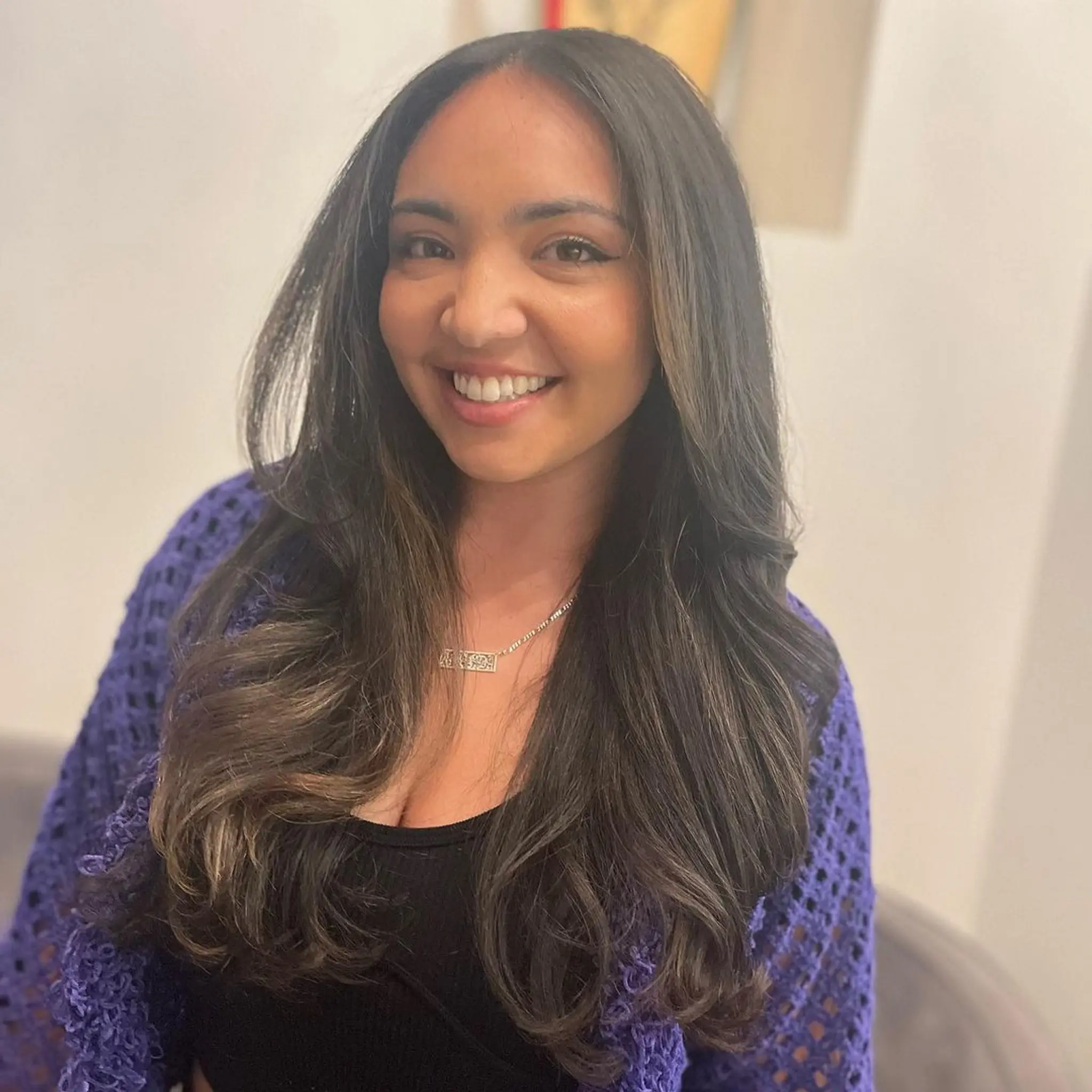 Very long, wavy hair with layered ends, subtle waves, and caramel highlights. Face-framing layers and a middle part create a balanced, elegant look.