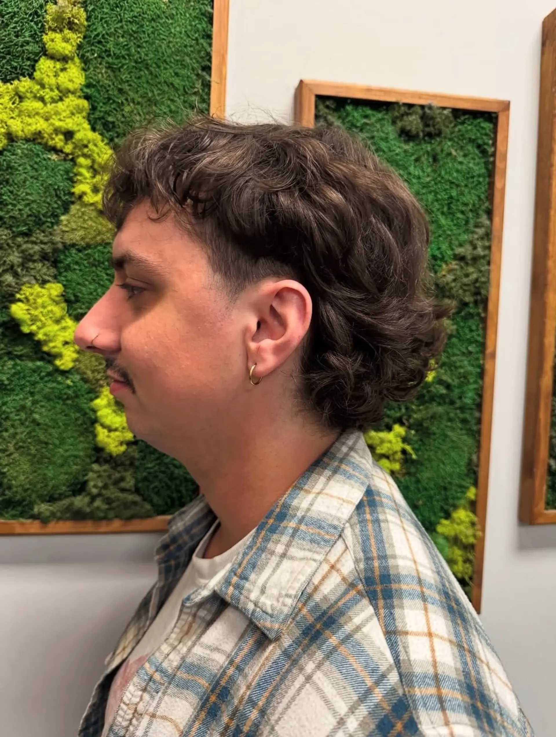 A textured, wavy modern mullet with cropped sides around the ears and fuller length down the nape. 1