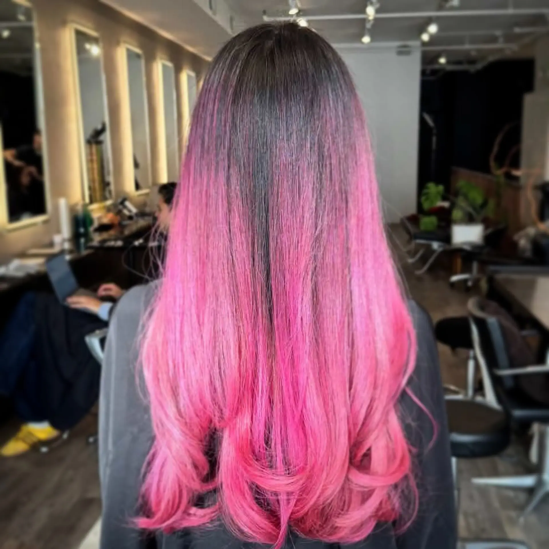 Long hair featuring a seamless transition from dark roots to vivid hot pink ends, styled in a sleek blowout with soft curls at the tips. 1