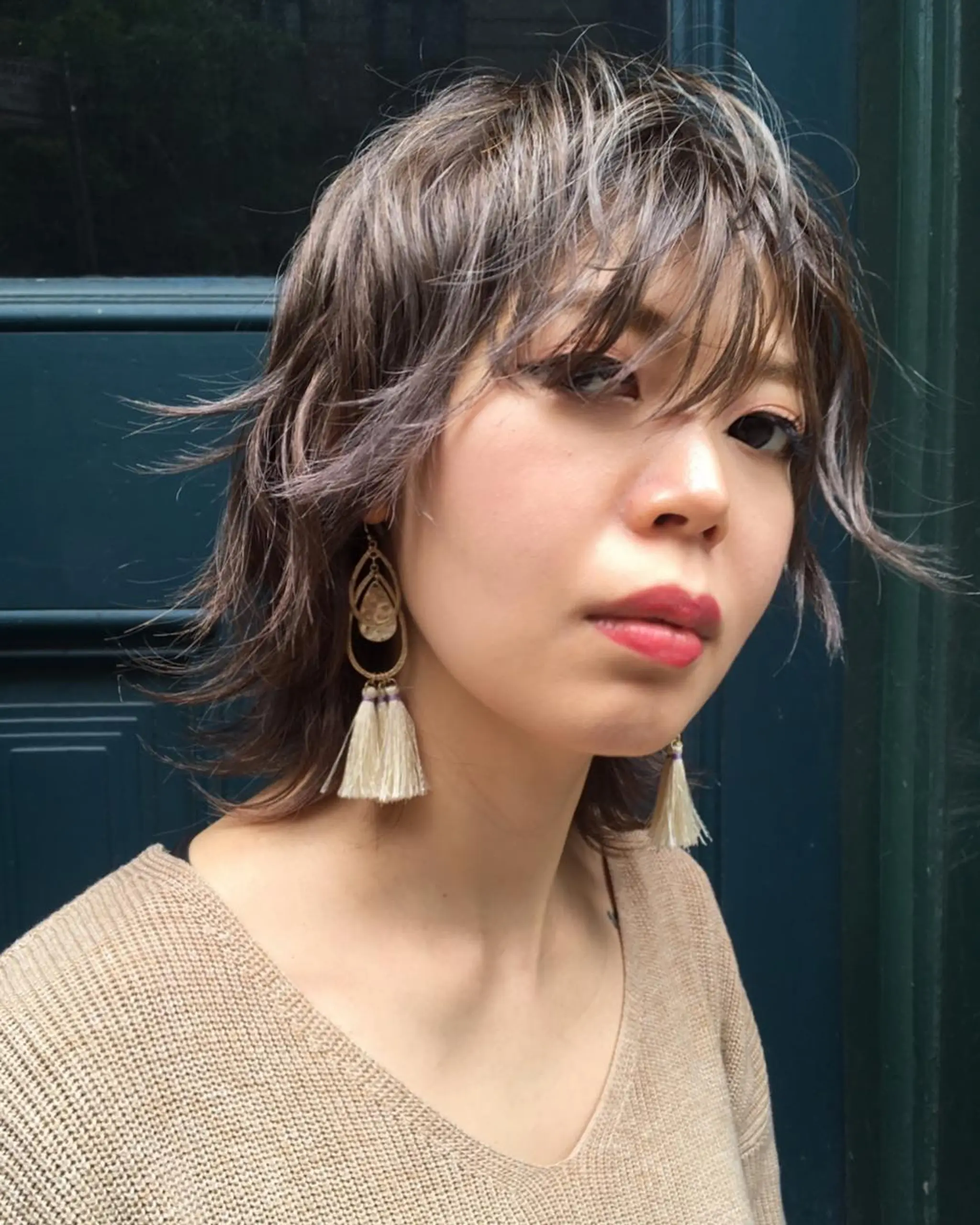 A medium-length, wavy bob cut with textured layers and a feathered fringe that offers a tousled yet sophisticated look.
