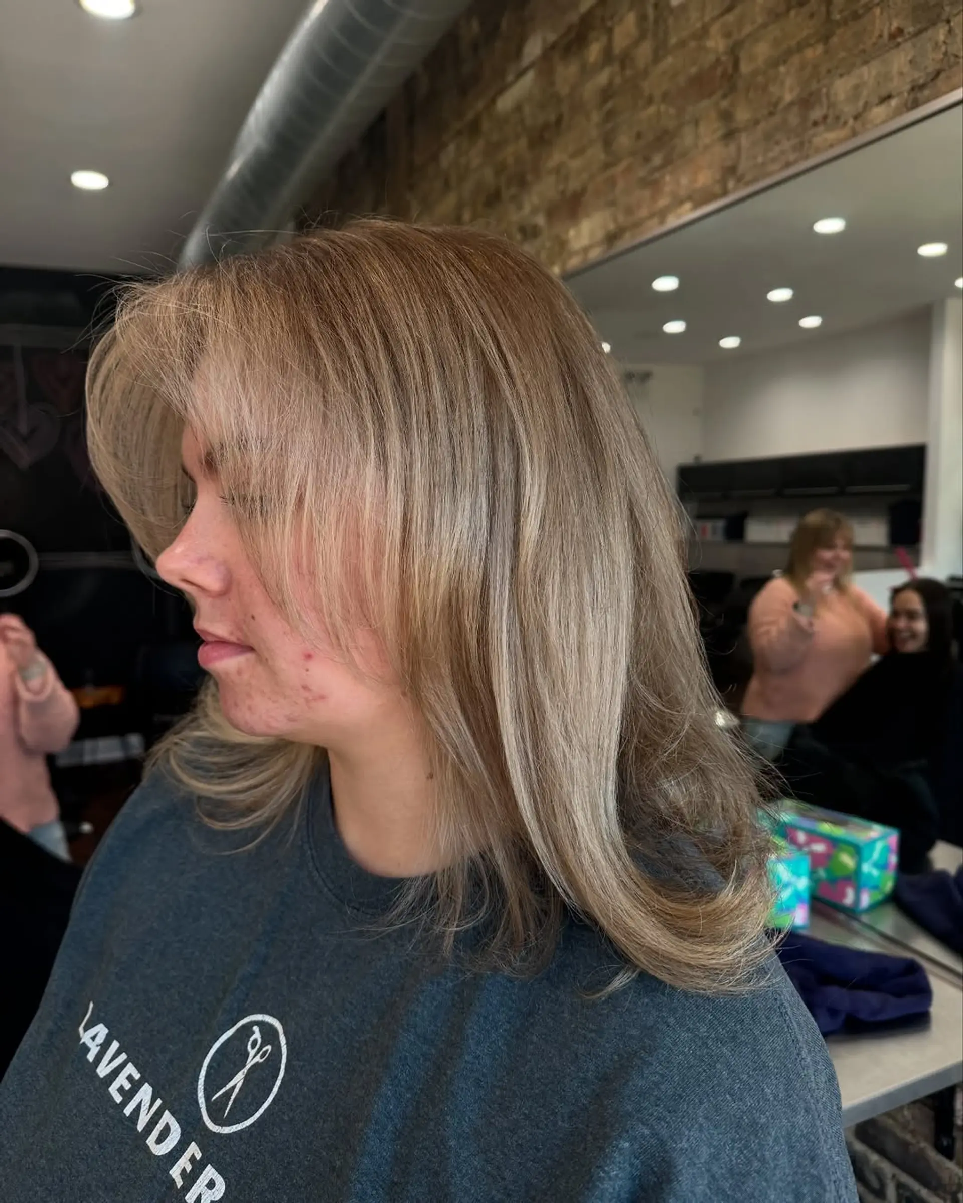 A chic medium-length haircut featuring soft layers that create volume and movement, styled with a smooth and voluminous blowout. The cut enhances body and provides a polished finish. 1