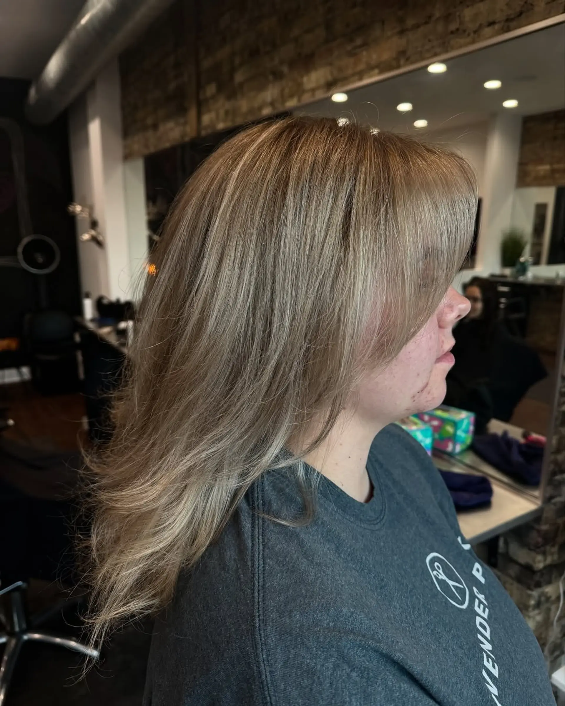 A chic medium-length haircut featuring soft layers that create volume and movement, styled with a smooth and voluminous blowout. The cut enhances body and provides a polished finish. 2