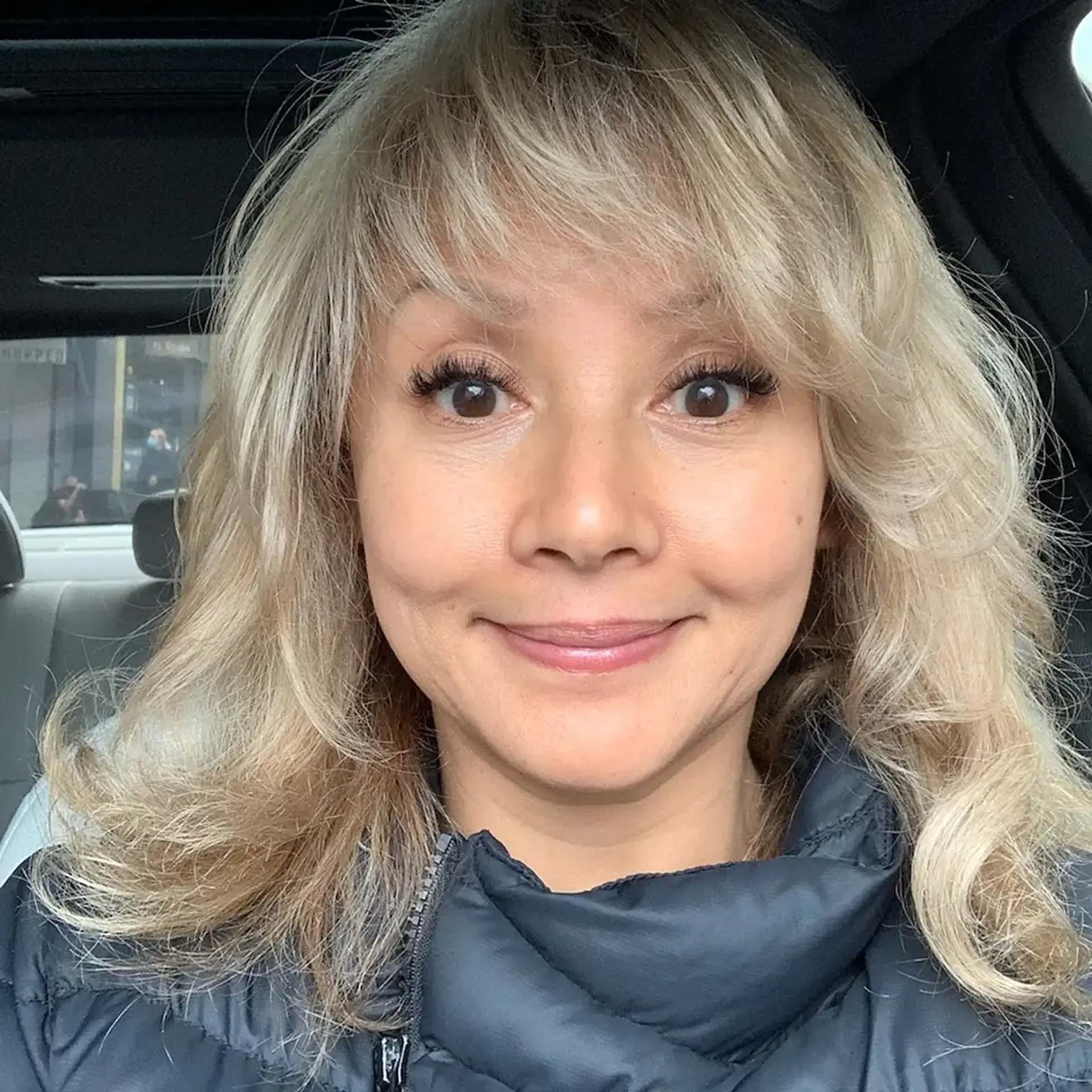 Medium-length layered hairstyle with soft, wispy bangs and dimensional ash blonde color. 1