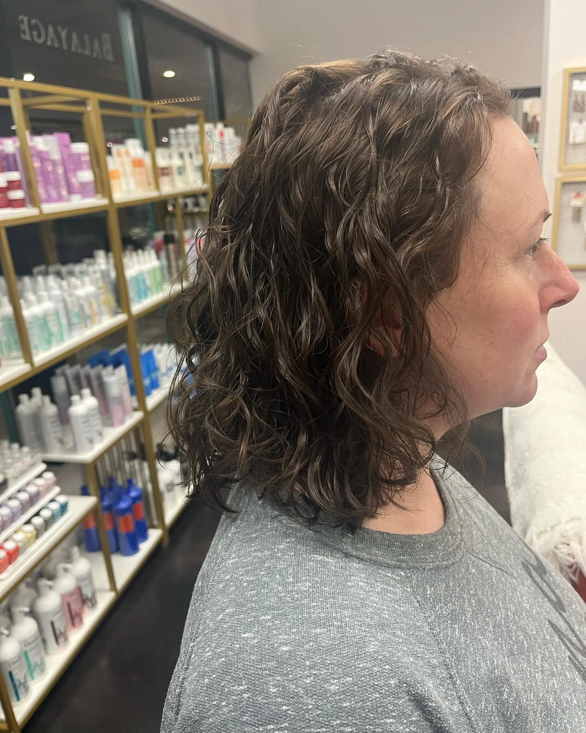 A shoulder-length layered curly lob showcasing defined, bouncy curls in a natural brunette shade. 1