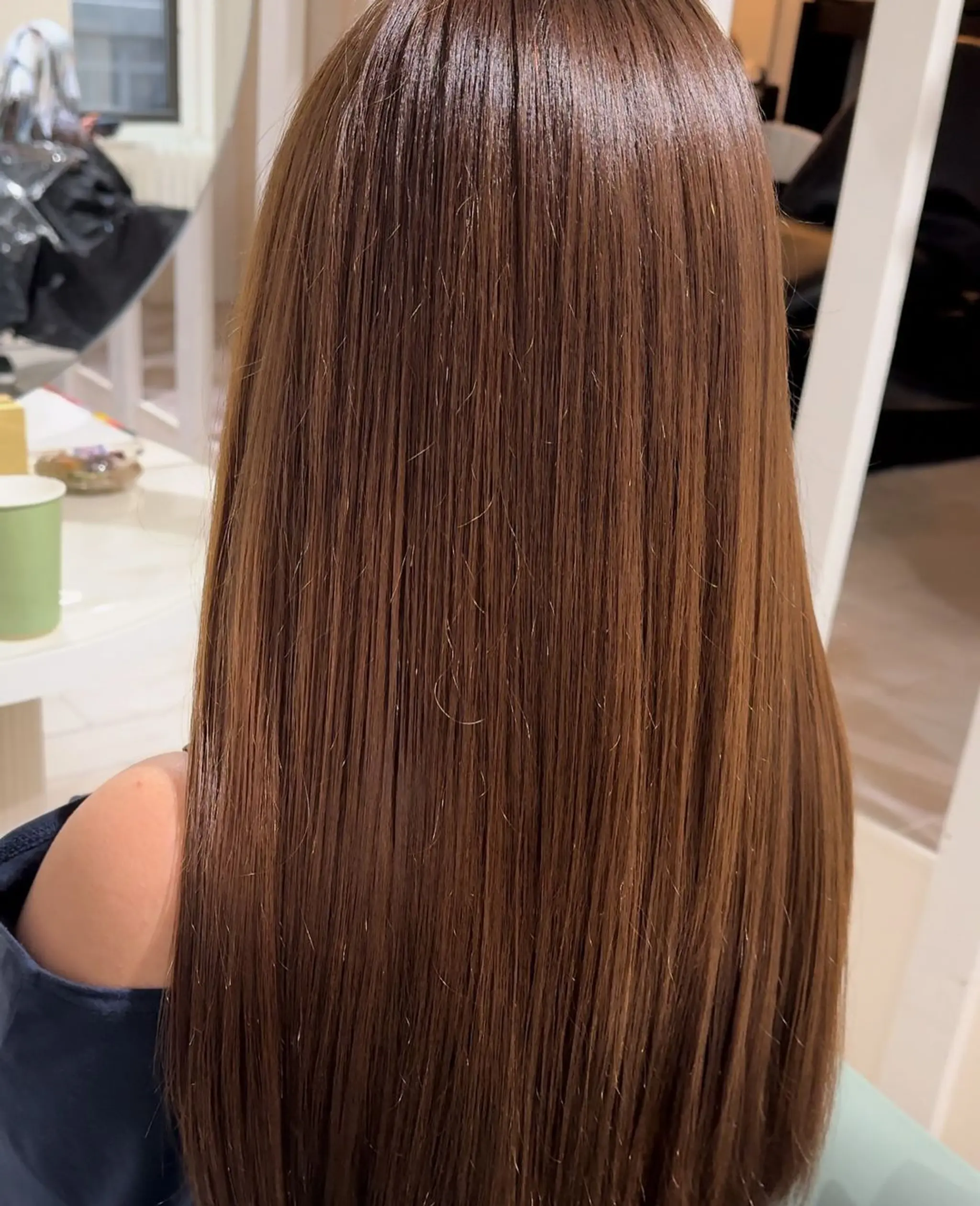 Long, straight hair with a silky, glossy finish and a natural chestnut brown color, evenly trimmed ends, and a healthy, well-moisturized appearance.