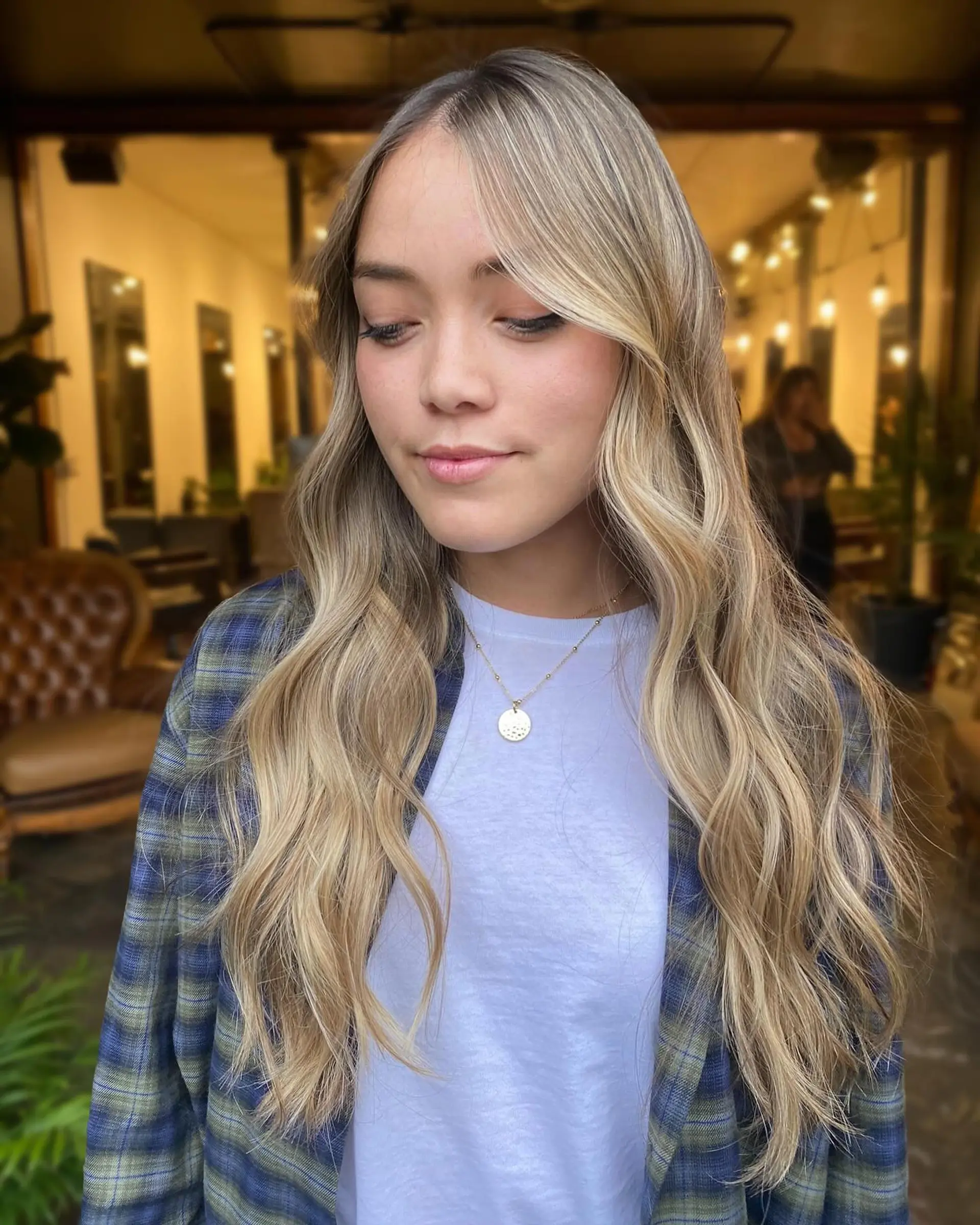 Long buttery blonde hair styled with loose, dimensional waves and face-framing layers. 1