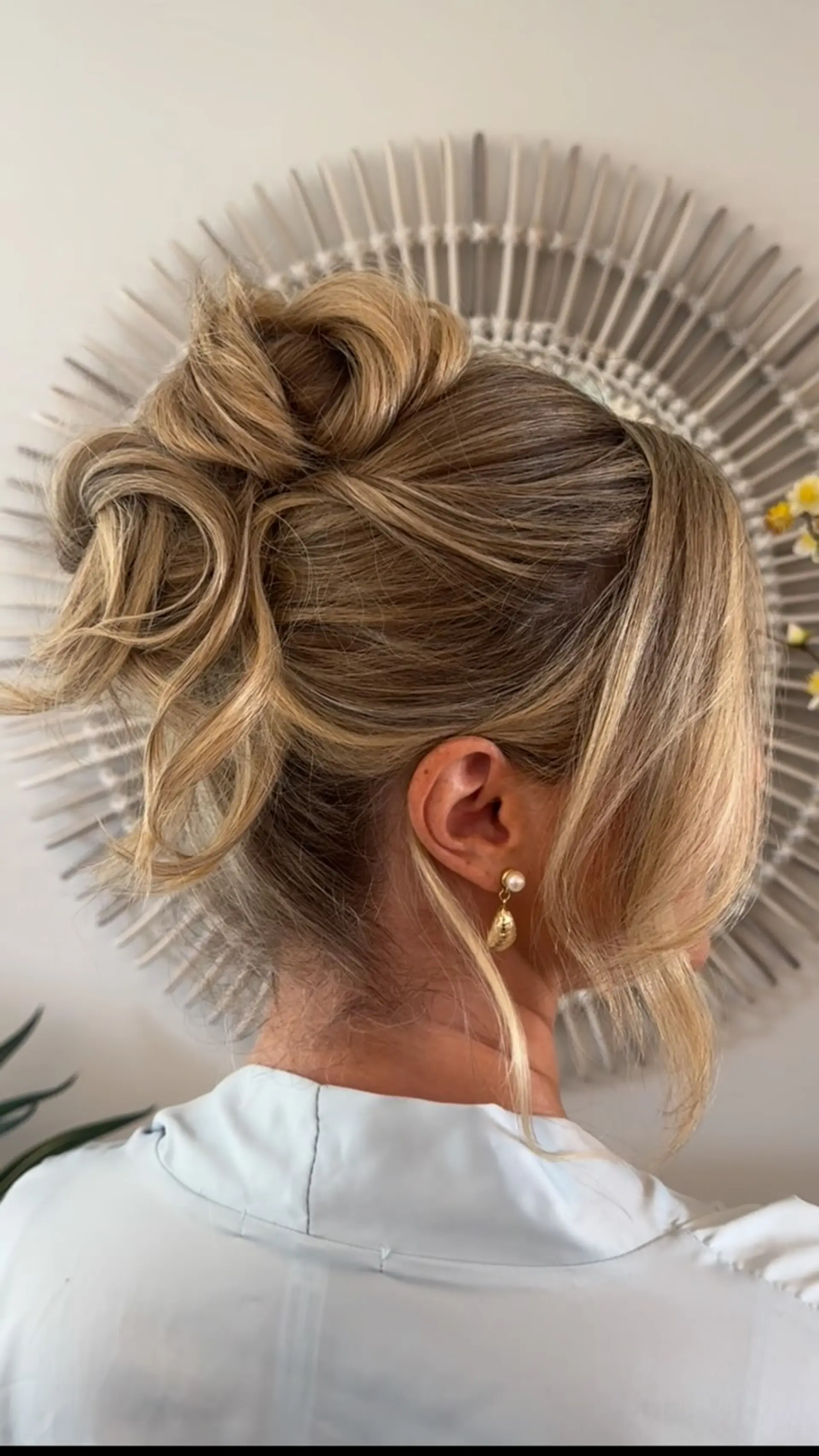 A textured high updo with soft curls pinned into a voluminous bun and loose face-framing pieces. 1