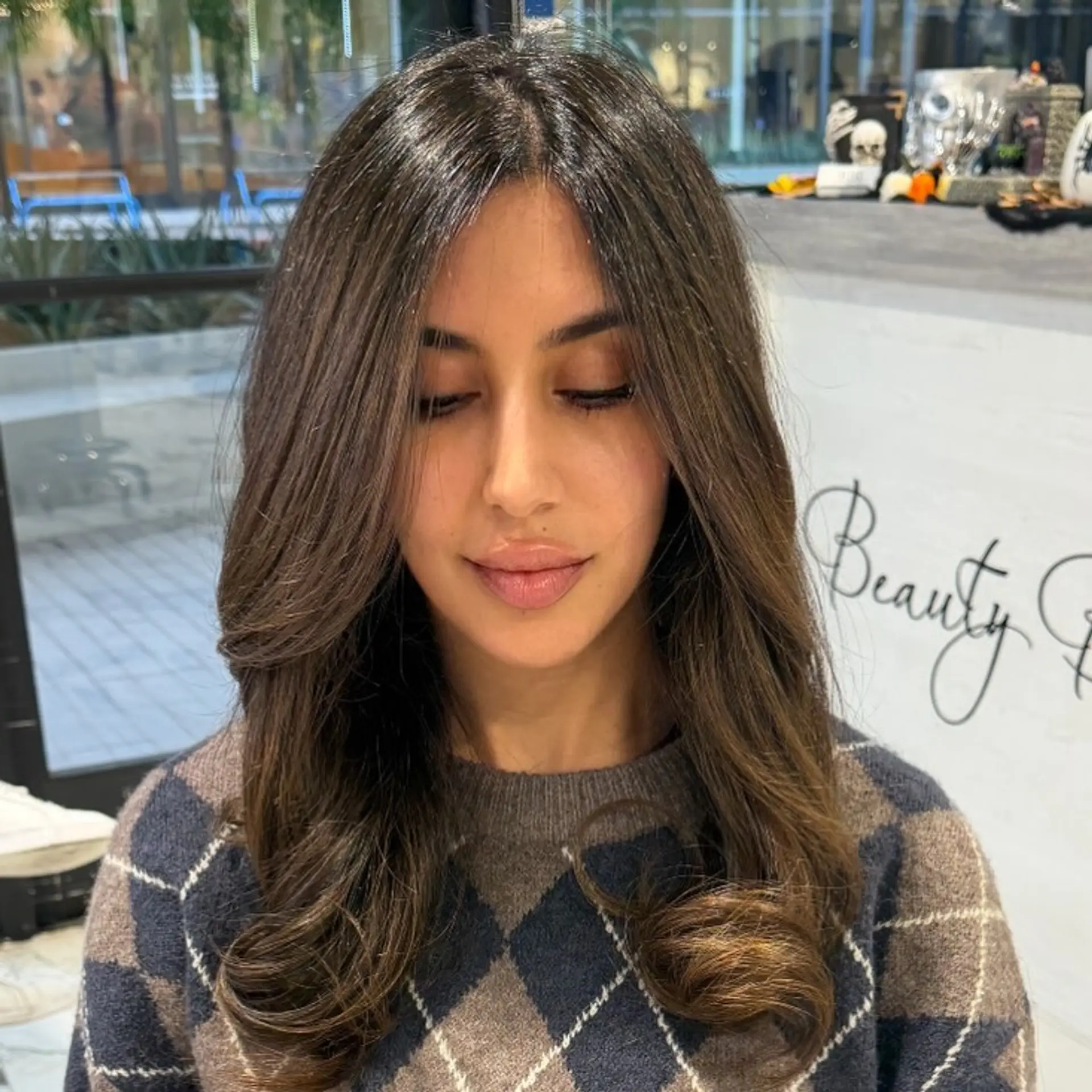 Long cool brunette hair styled in a smooth blowout with subtle highlights, face-framing curtain layers, and softly curled ends. 1