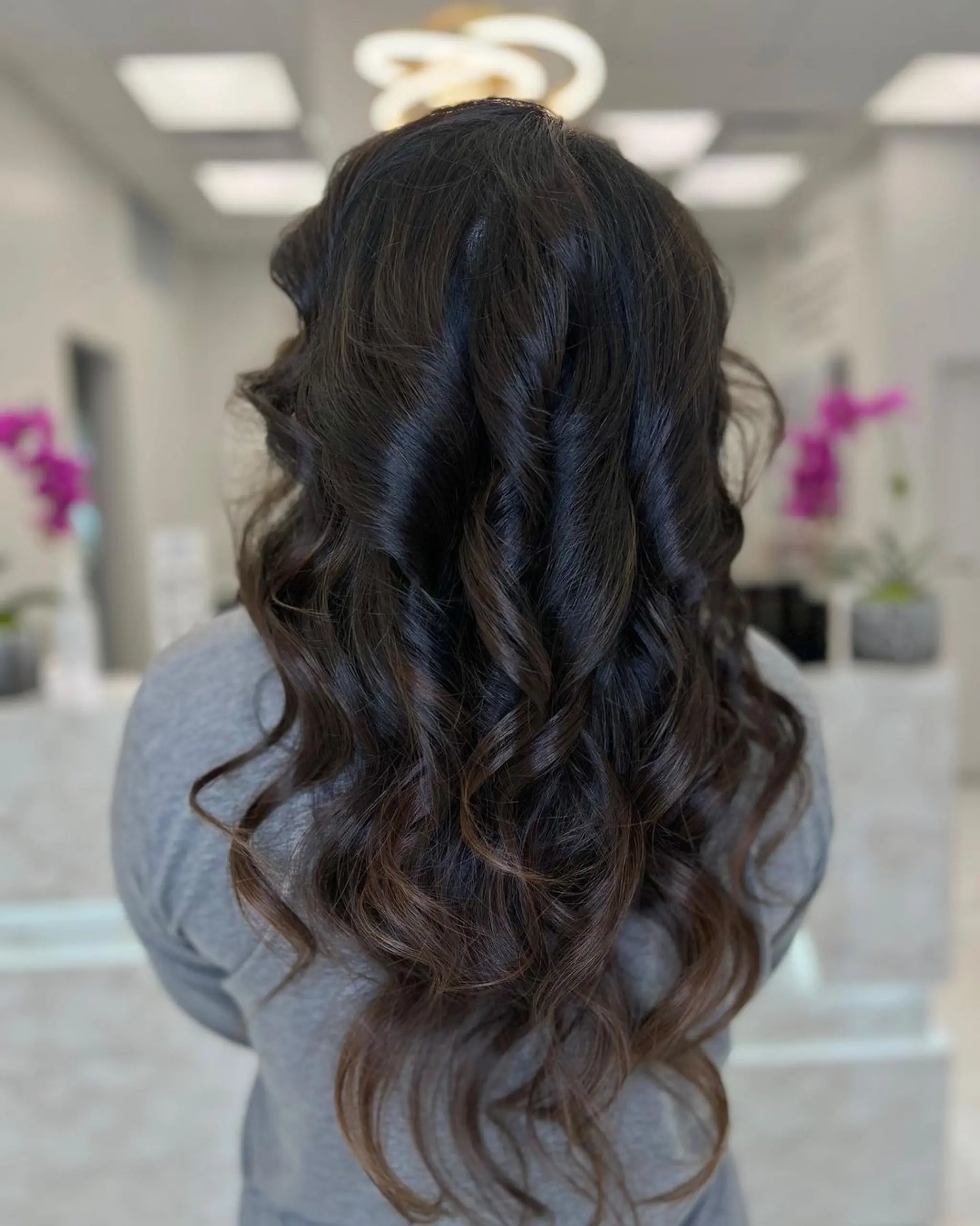 Long, cascading waves in dark brown with subtle highlights, featuring voluminous and soft flowing loose curls.