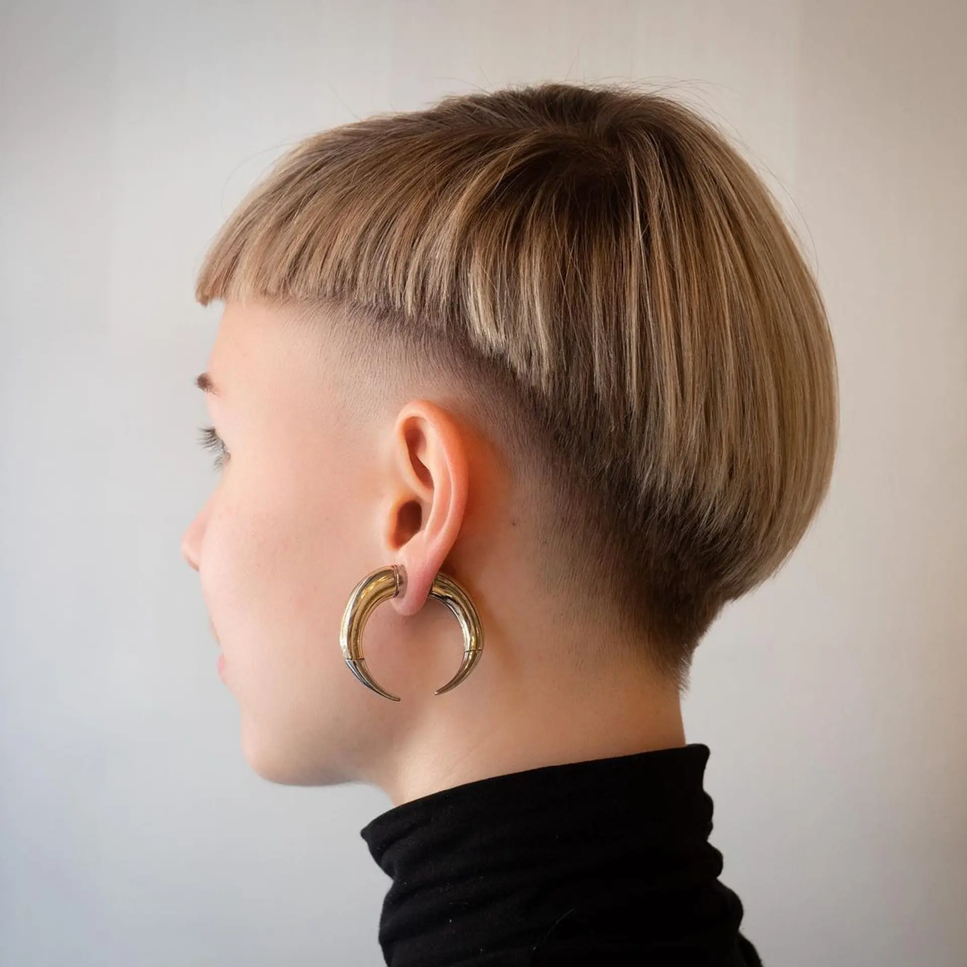 Short, edgy pixie bob with asymmetrical lengths and blunt fringe in a blonde hue. 2