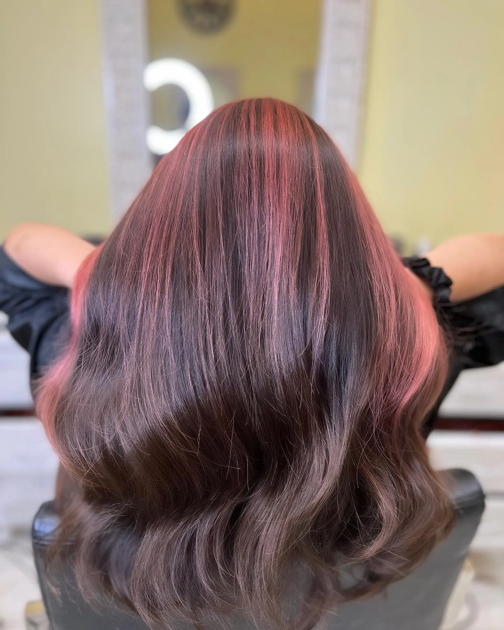 A long, straight hairstyle featuring a split dye technique with one side pink and the other dark brown. 2